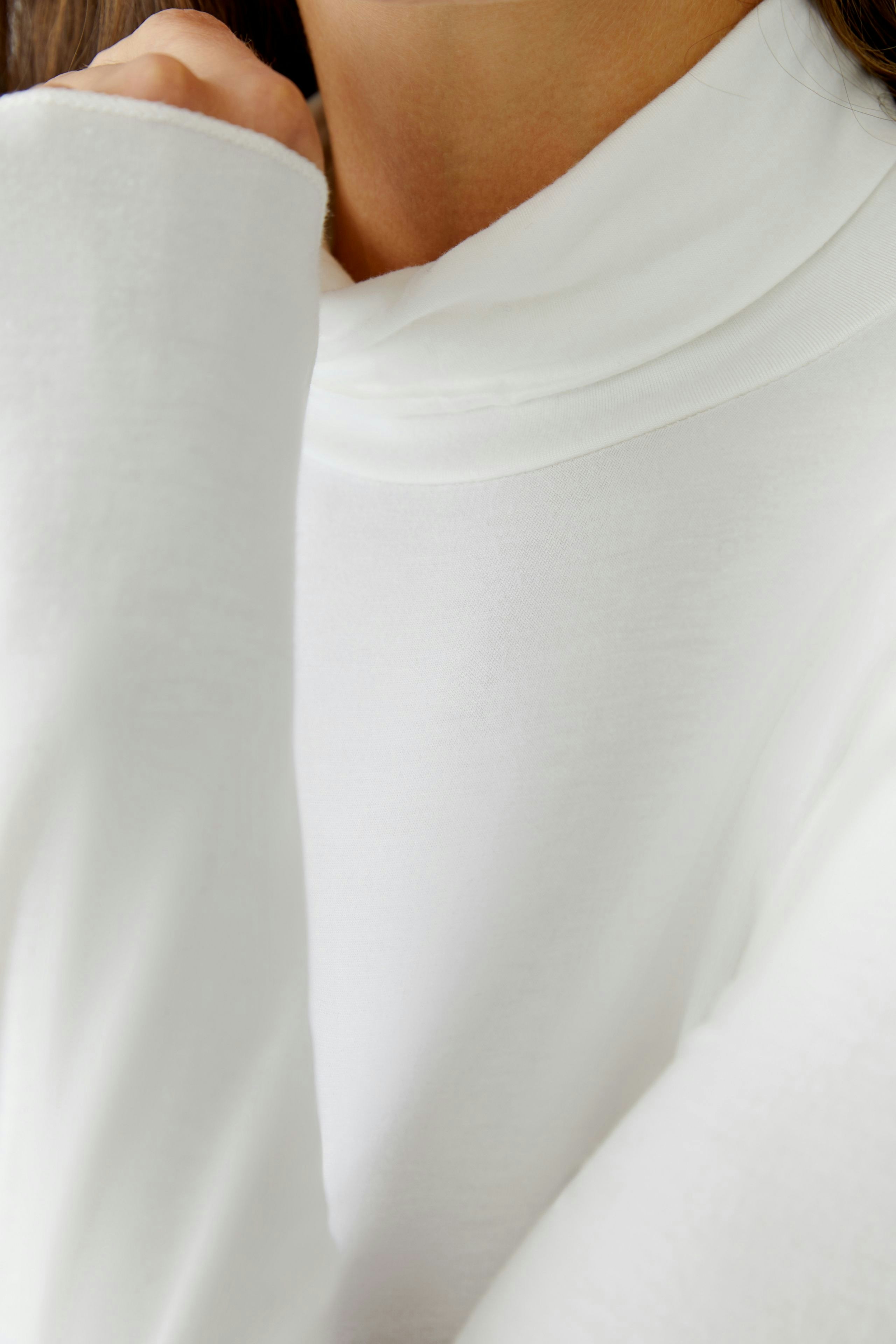 Casual women's long-sleeve shirt: Close-up of a woman in a white top with a cozy collar.