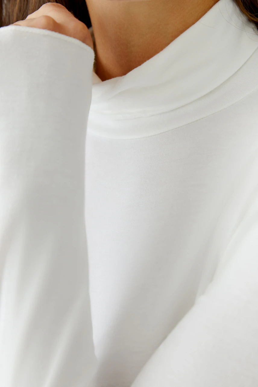Casual women's long-sleeve shirt: Close-up of a woman in a white top with a cozy collar.