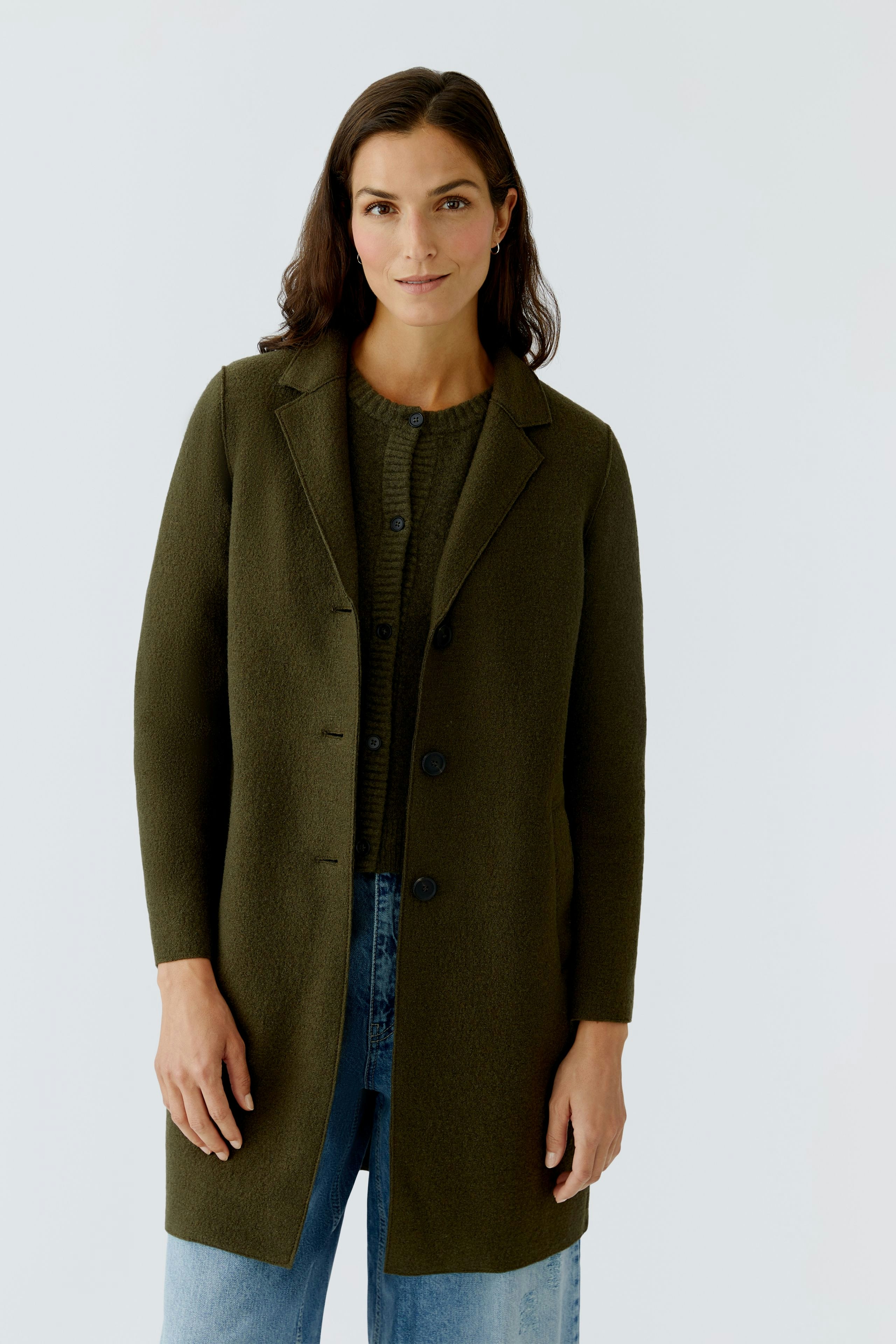 Damen Wollmantel: Frau in grünem Wollmantel mit Knöpfen und lässigem Look.