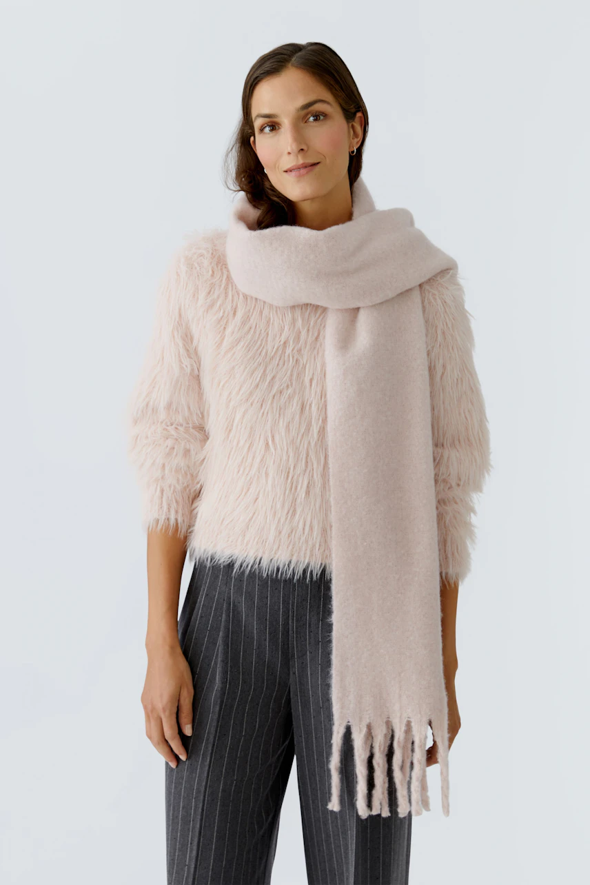 Weicher Damen-Schal in zartem Rosa, lässig um den Hals drapiert, ergänzt den Look.