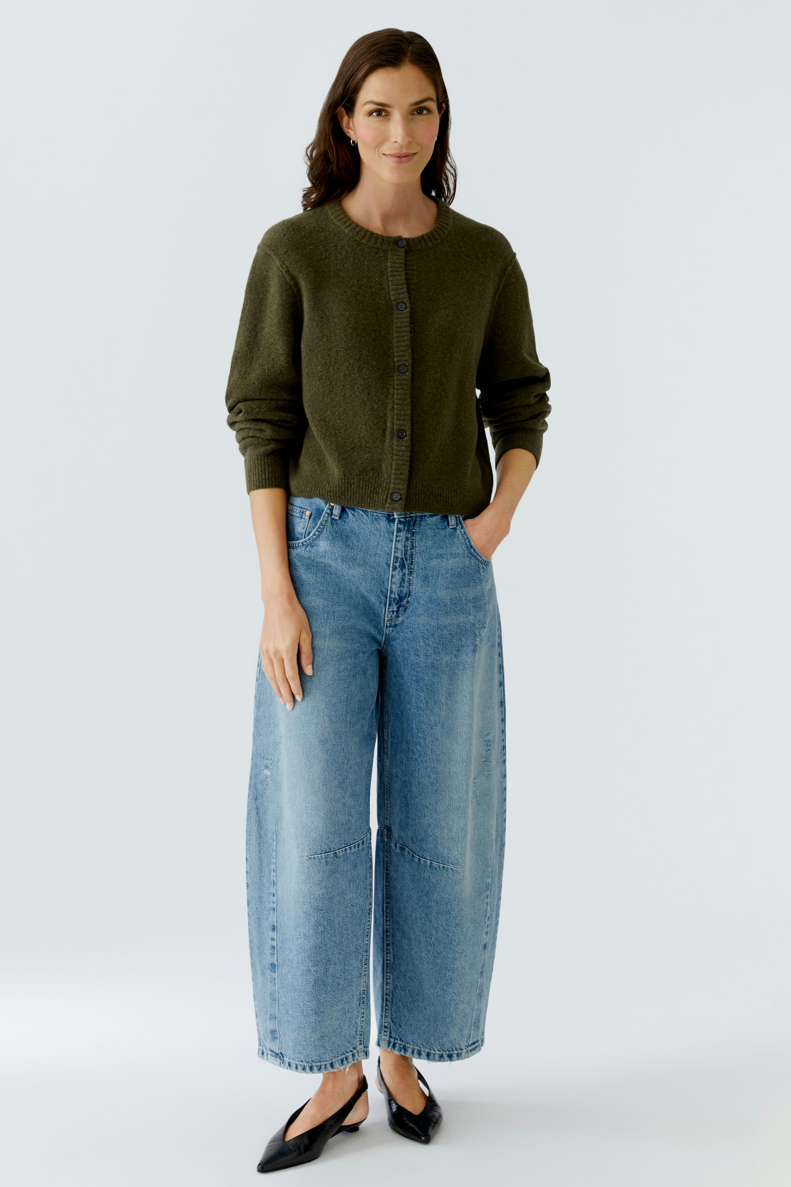 Damen-Strickjacke: Frau in olivgrüner Strickjacke mit Knöpfen und lässigen Jeans.