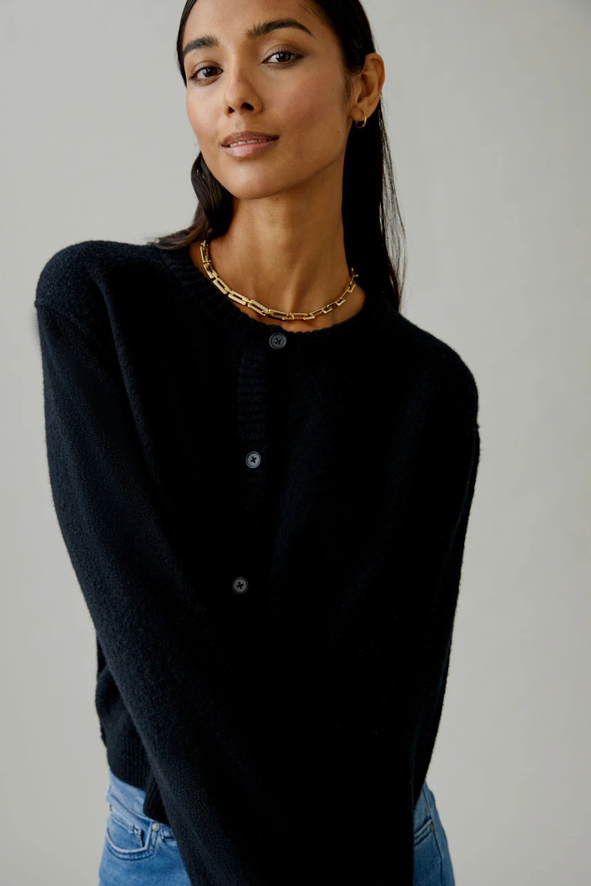 Damen-Strickjacke: Frau in schwarzer Strickjacke mit Knöpfen und lässigem Look.