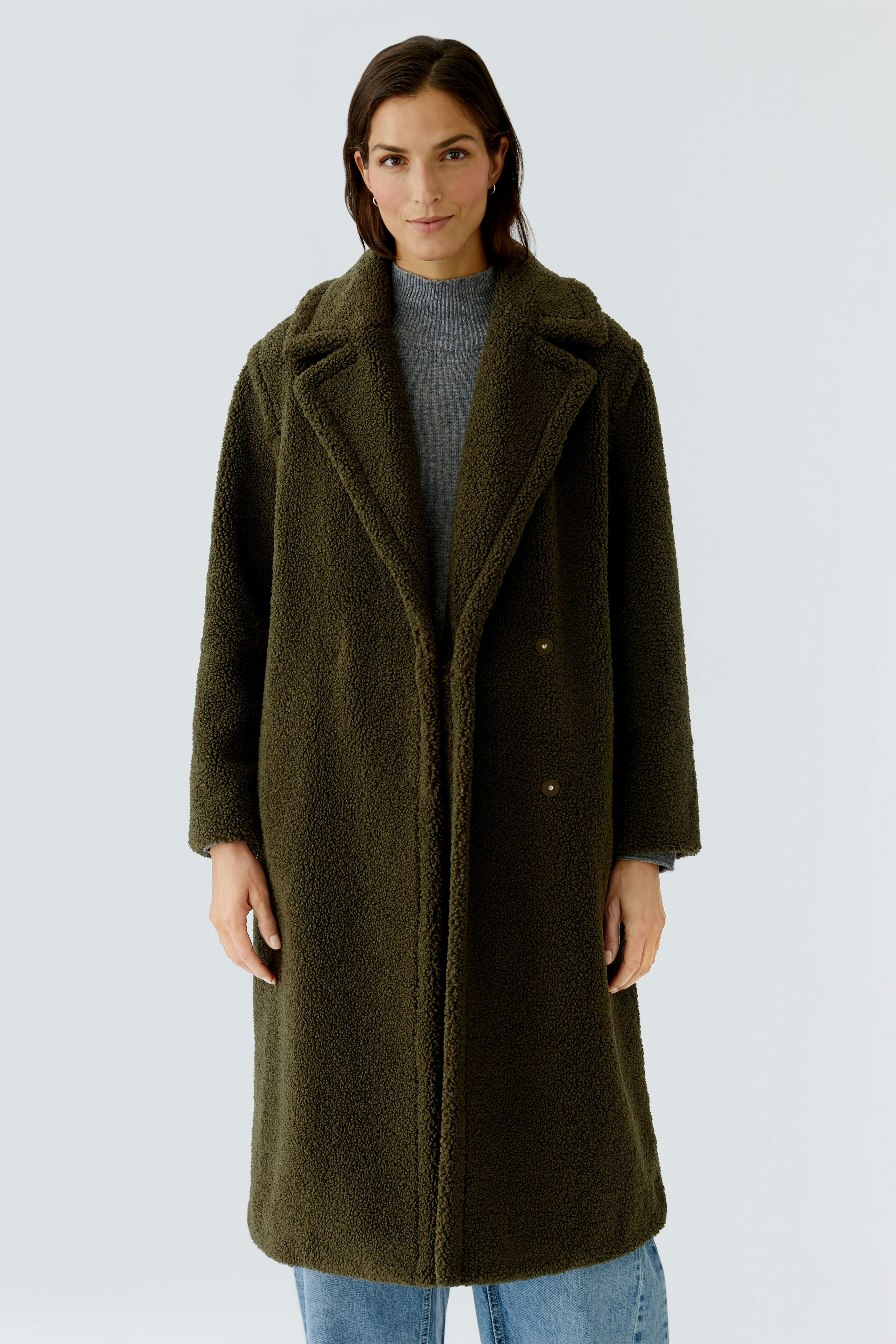 Cozy women's winter coat: A woman in a soft, olive green coat stands confidently against a light background.