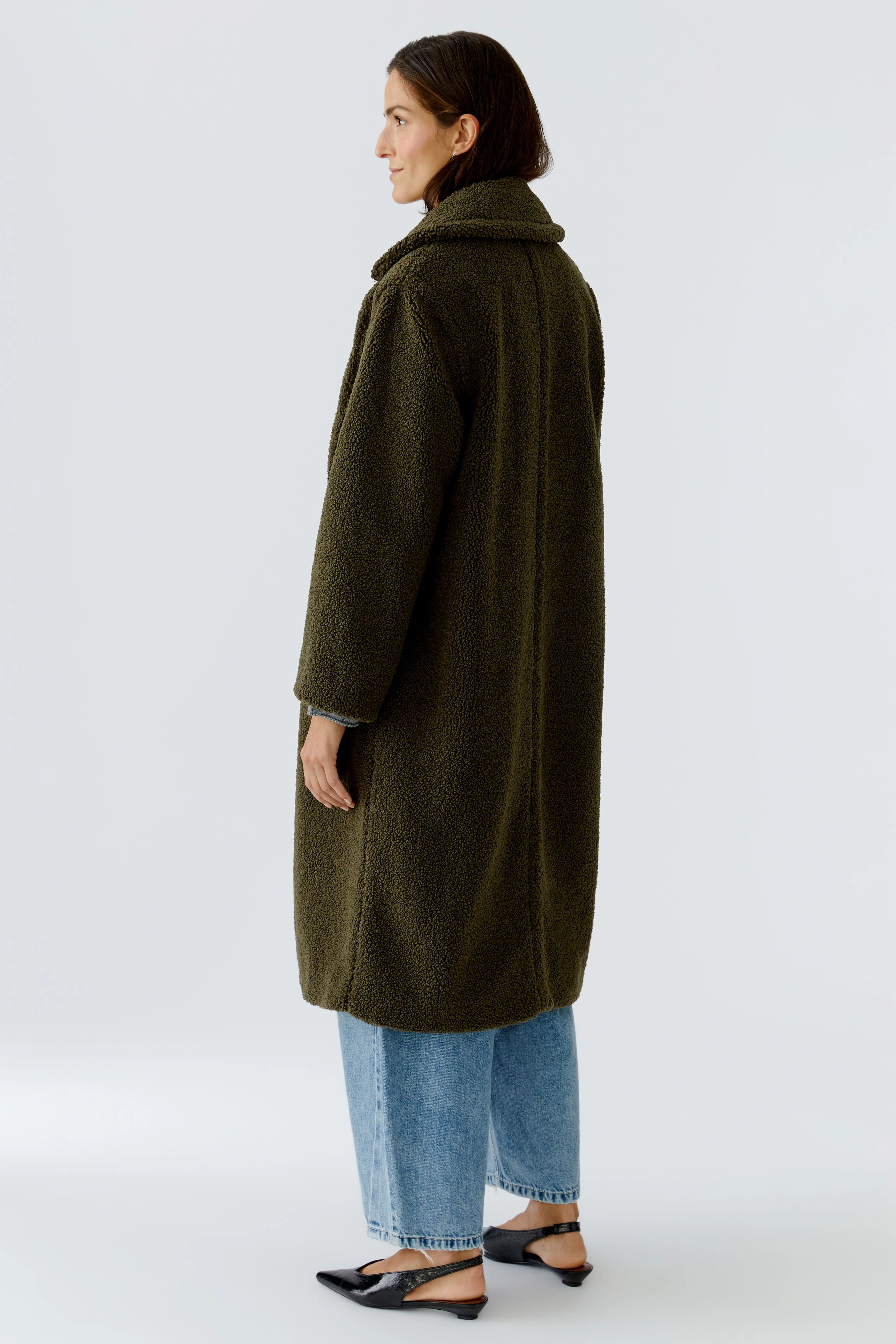 Cozy women's winter coat: A woman in a soft, olive green coat with a relaxed fit, paired with jeans.