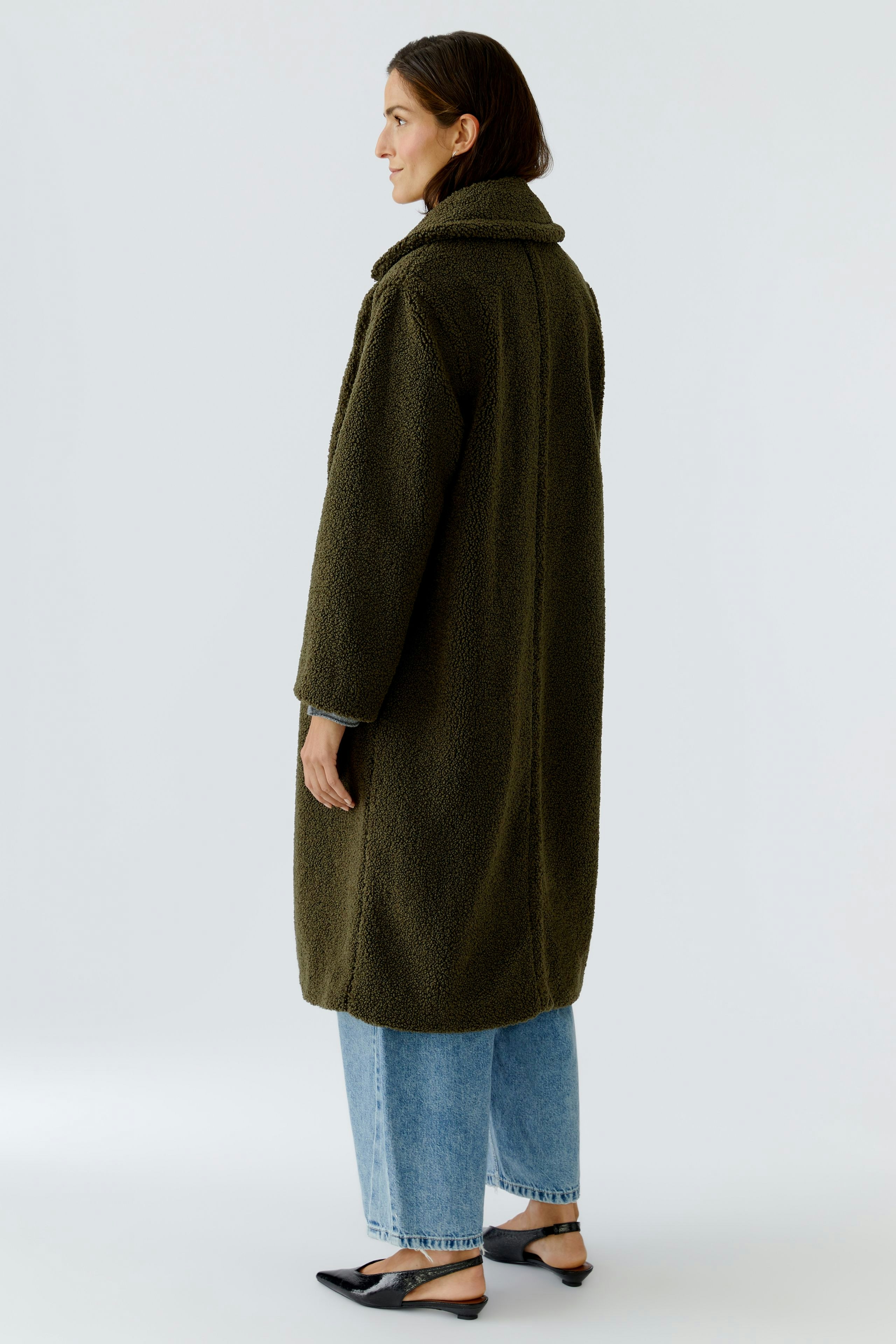 Cozy women's winter coat: A woman in a soft, olive green coat with a relaxed fit, paired with jeans.