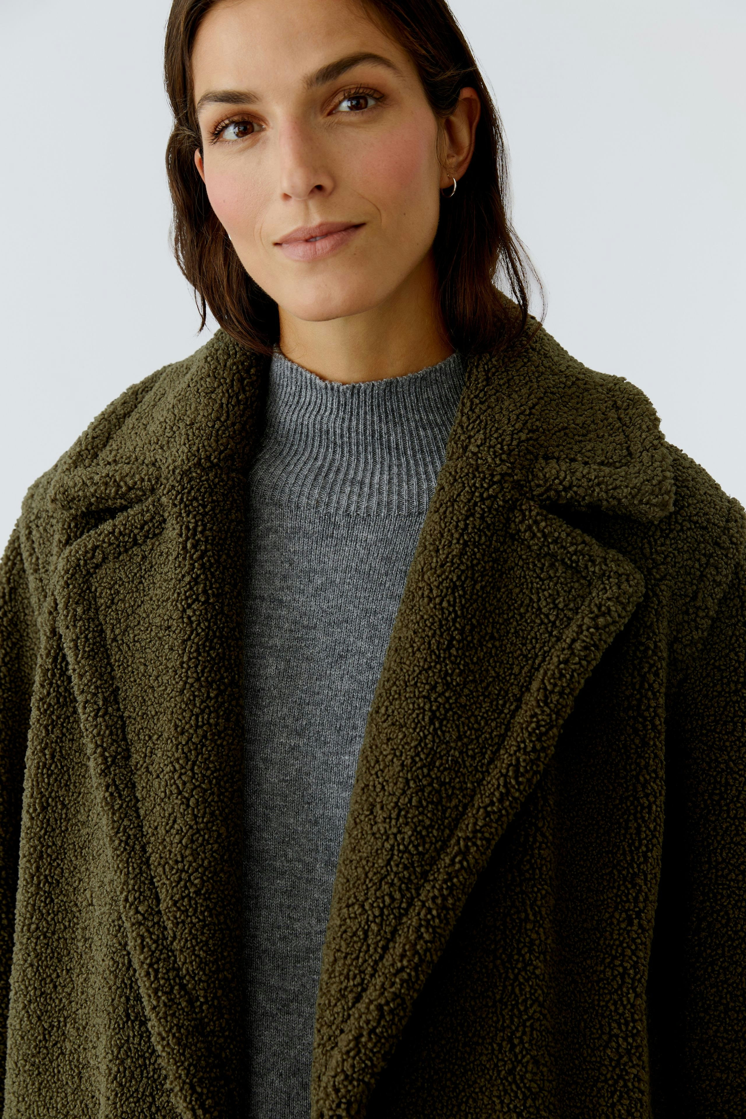 Cozy women's winter coat: A woman in a soft, olive green coat with a relaxed fit and wide lapels.