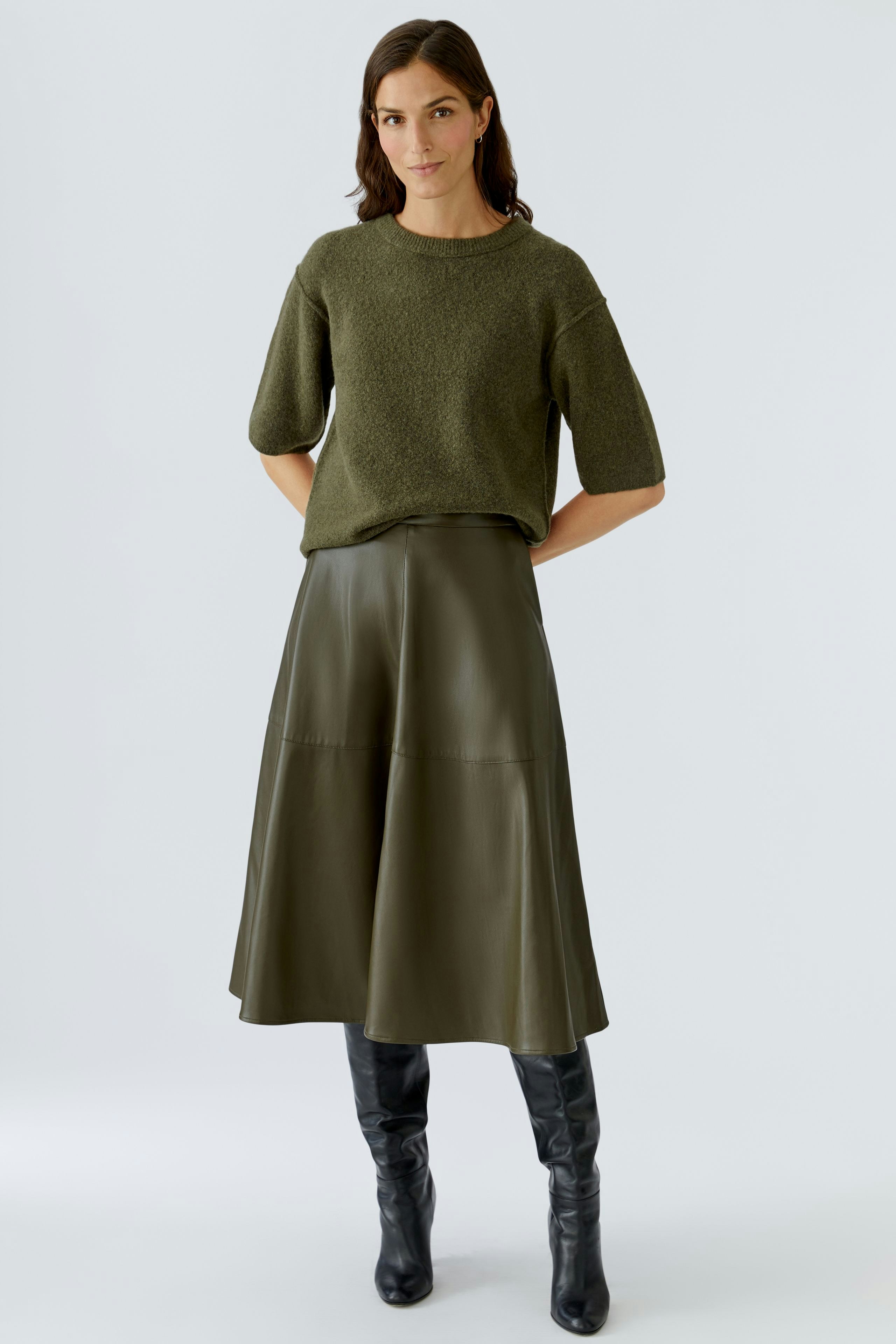 Casual women's pullover: A woman in a green textured pullover paired with a leather skirt.
