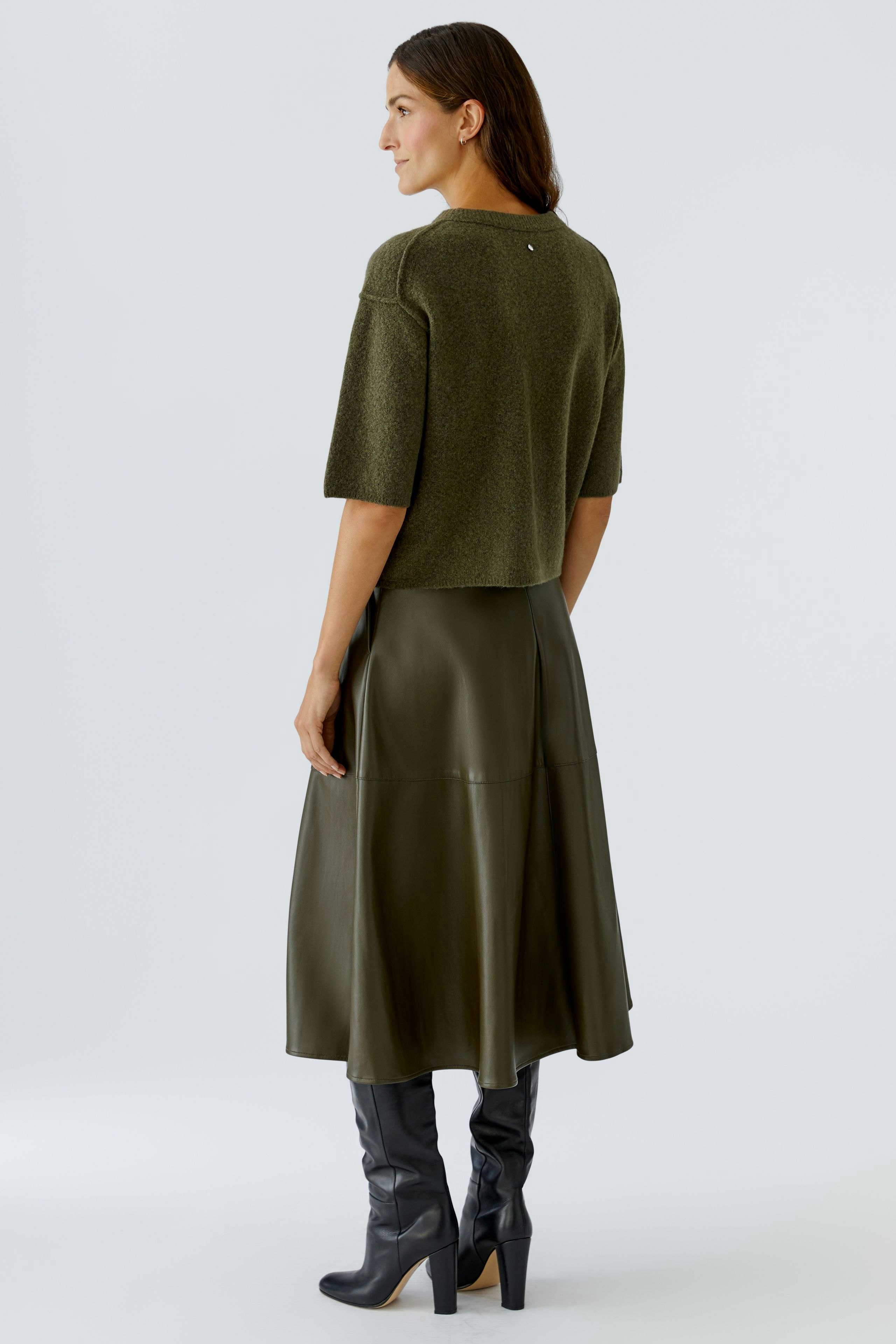 Casual women's pullover: A woman in a cropped olive pullover paired with a long skirt and knee-high boots.