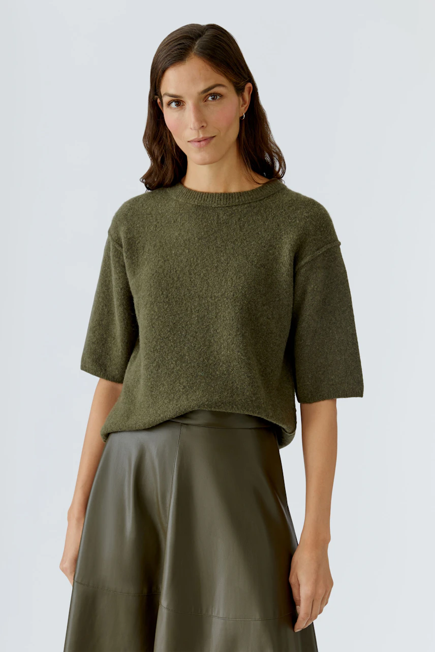 Casual women's pullover: A woman in a green short-sleeve pullover paired with a leather skirt.