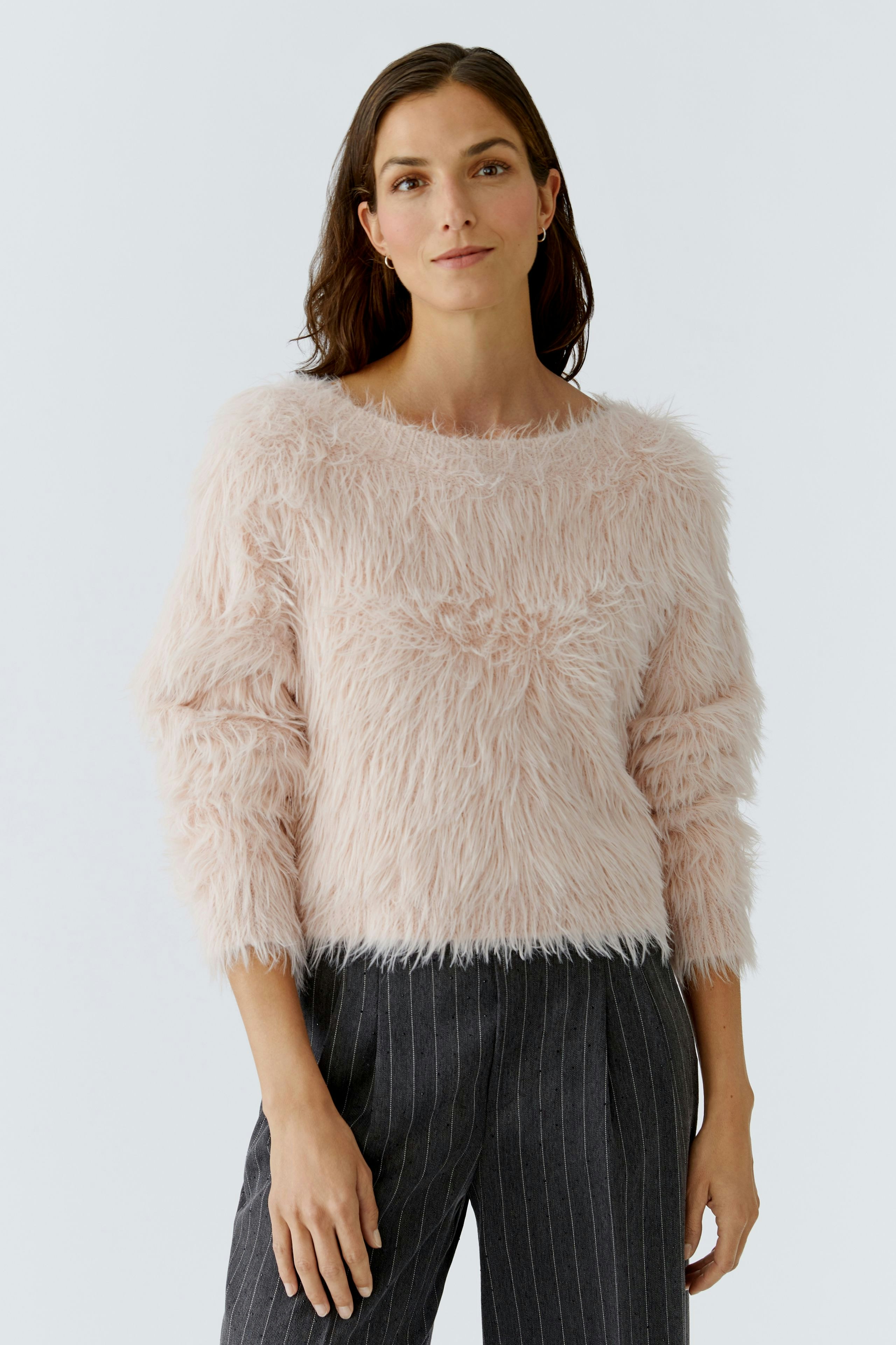 Soft pink pullover: Woman in a fluffy pullover paired with striped pants, exuding a relaxed vibe.