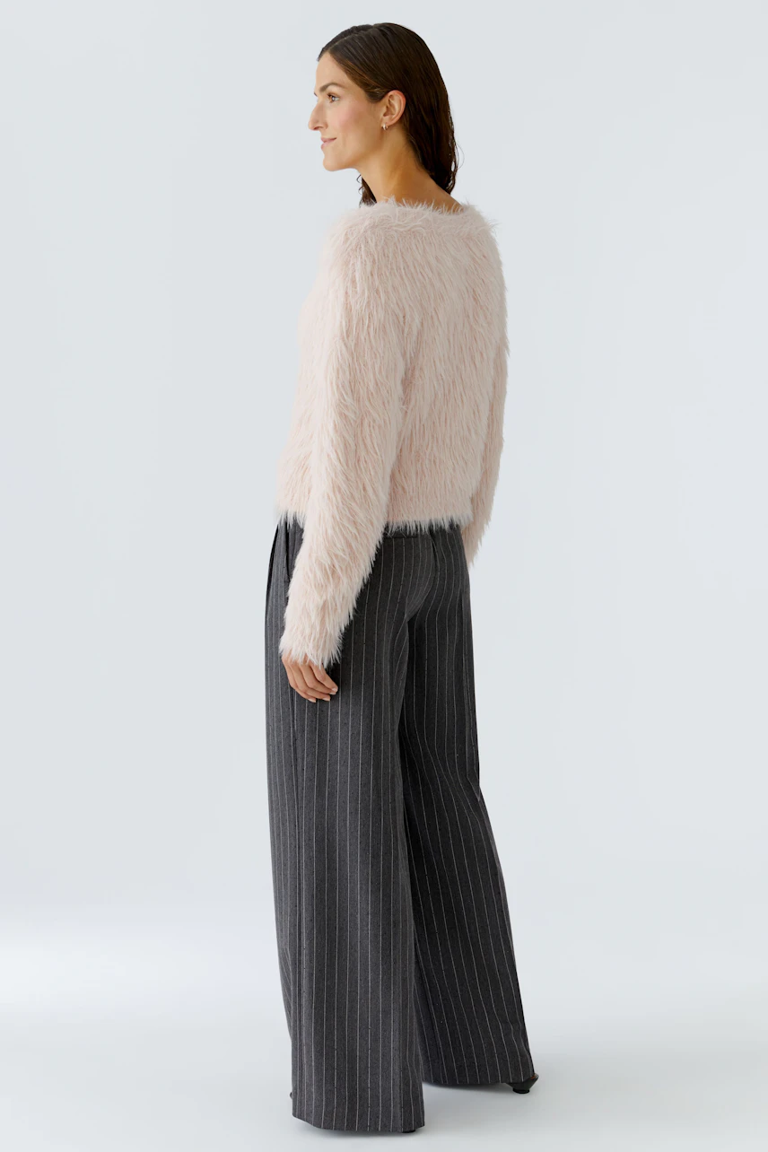 Soft pink pullover: Woman in a fluffy pullover paired with wide striped pants, showcasing a relaxed style.