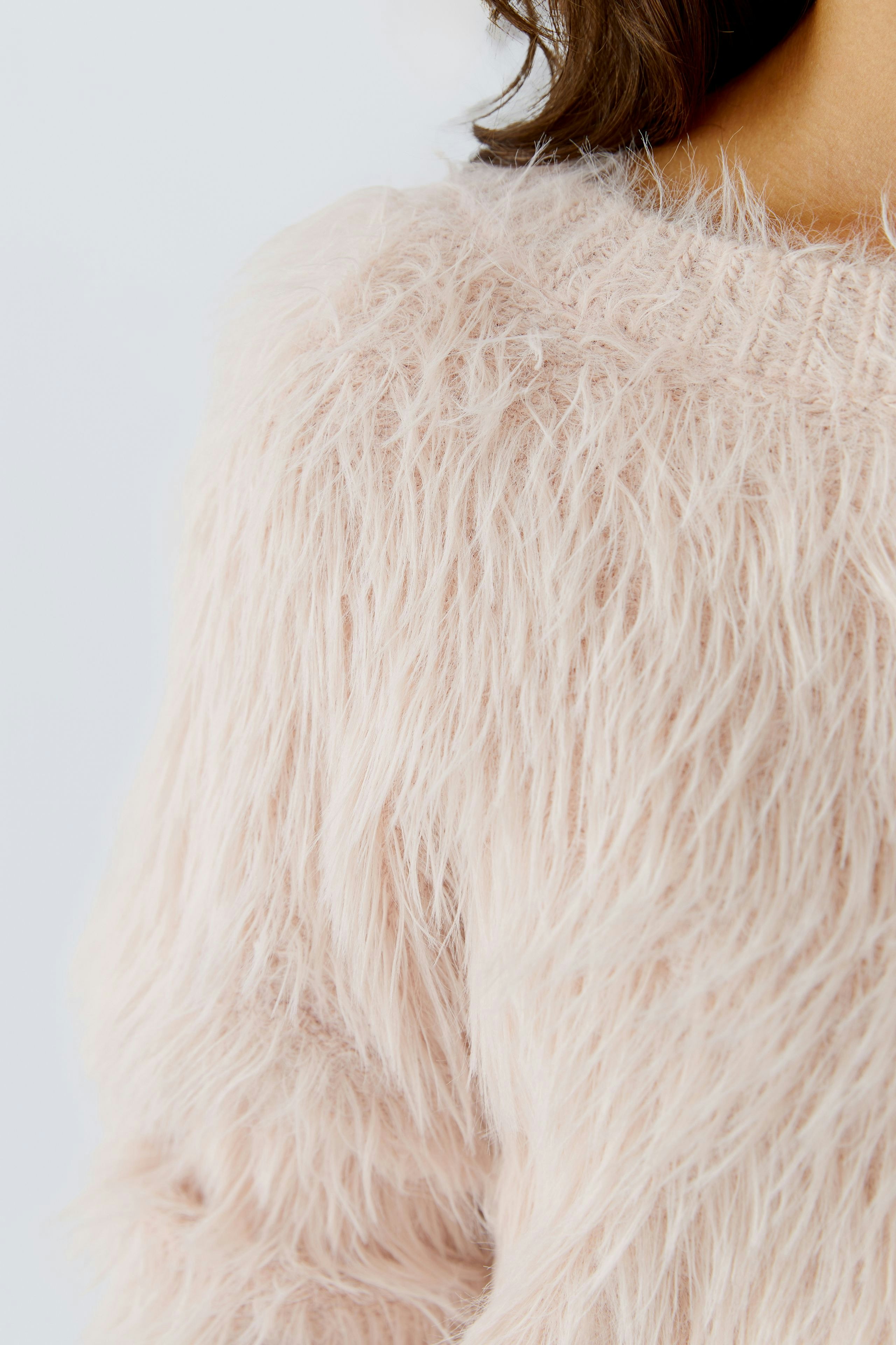 Soft pink pullover: Close-up of a woman's fluffy pullover with a cozy texture.