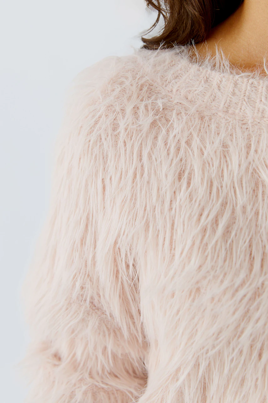 Soft pink pullover: Close-up of a woman's fluffy pullover with a cozy texture.