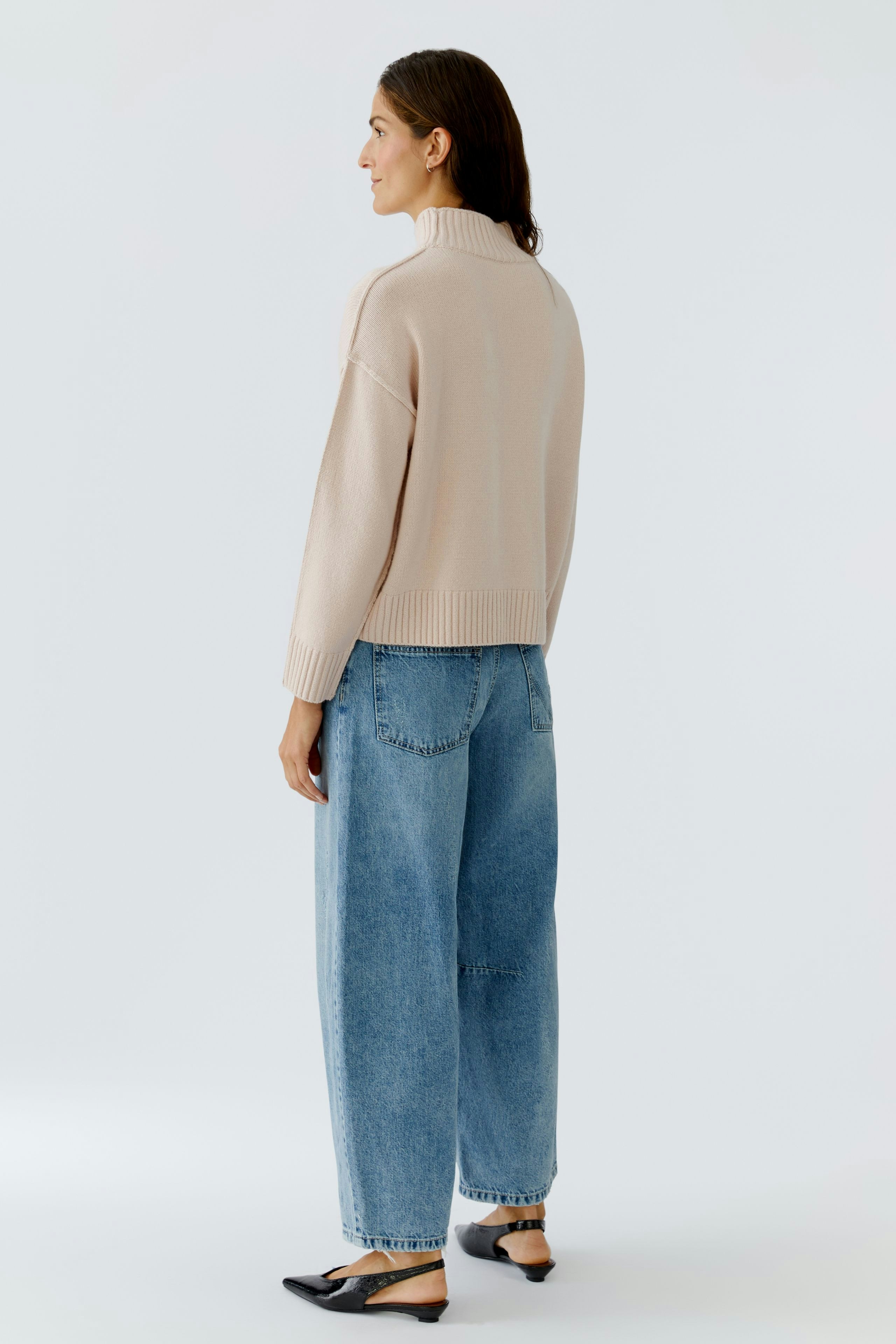 Casual women's pullover: A woman in a light beige pullover with a relaxed fit and wide jeans.