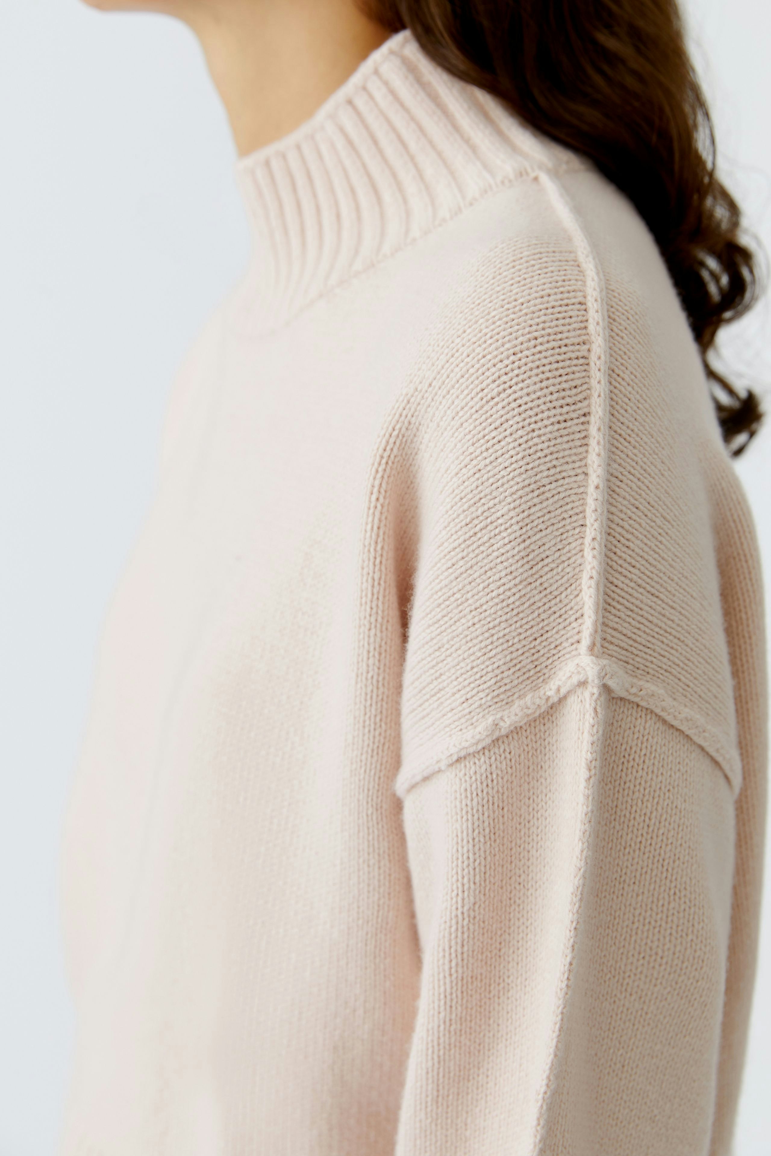 Casual women's pullover: Close-up of a woman in a soft pink pullover with a ribbed collar.