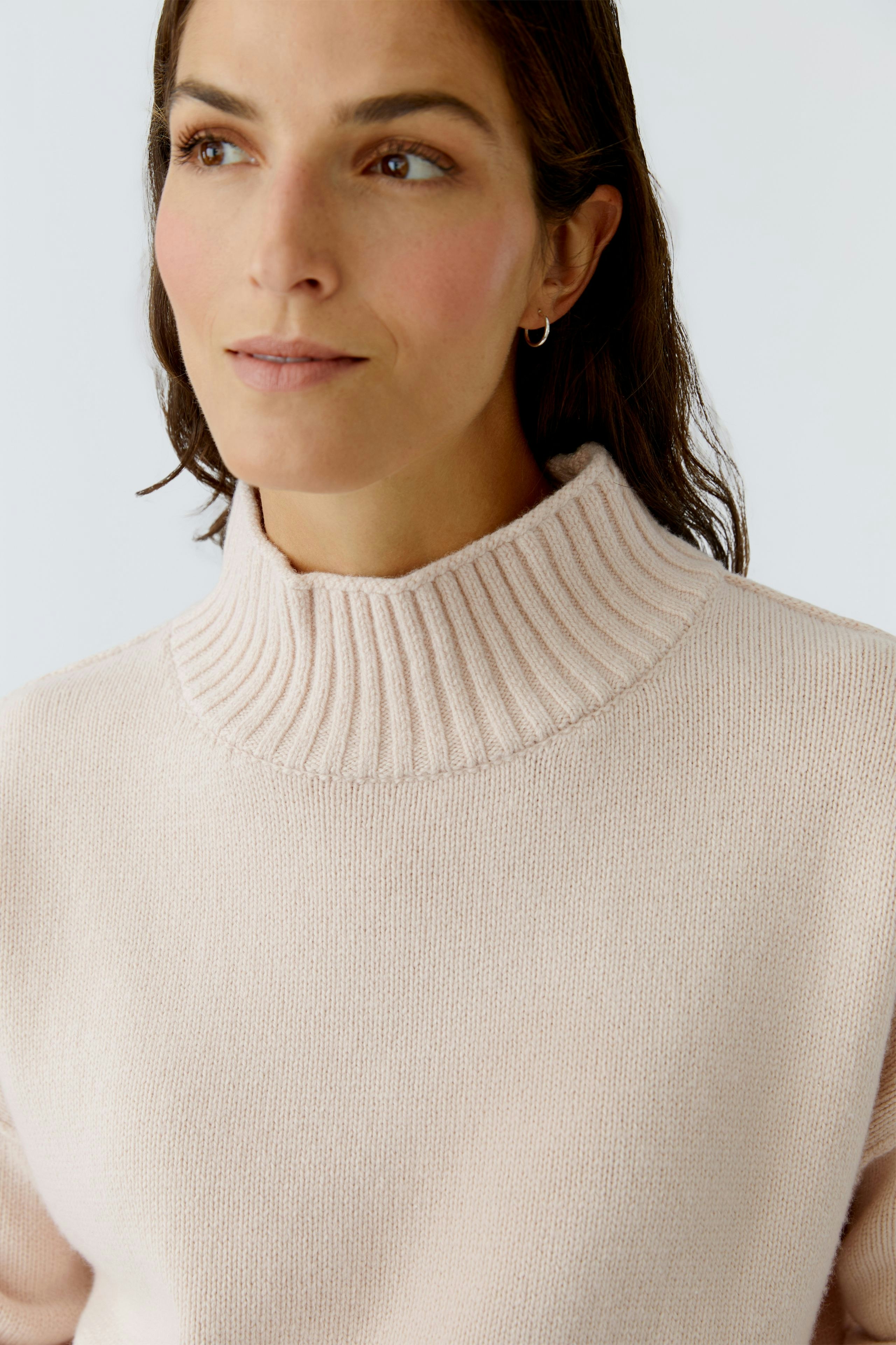 Casual women's pullover: Close-up of a woman in a soft pink pullover with a ribbed collar.