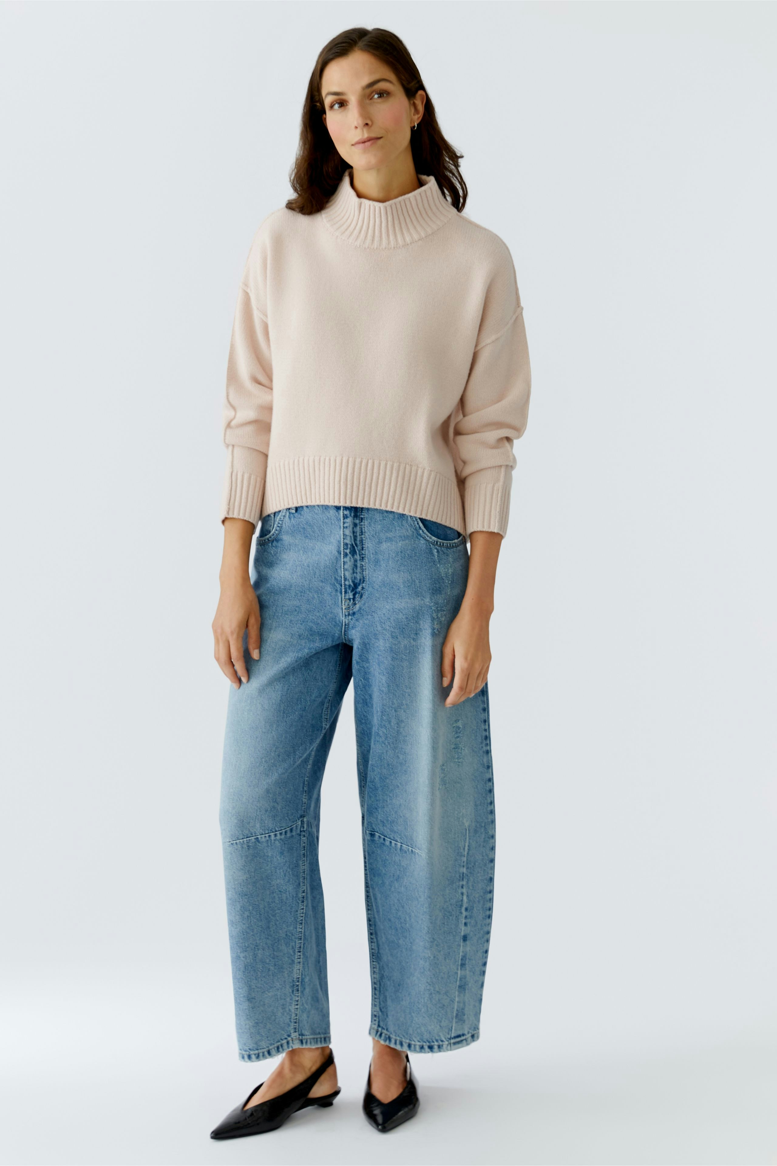Casual women's pullover: A woman in a light pink pullover paired with relaxed-fit jeans.