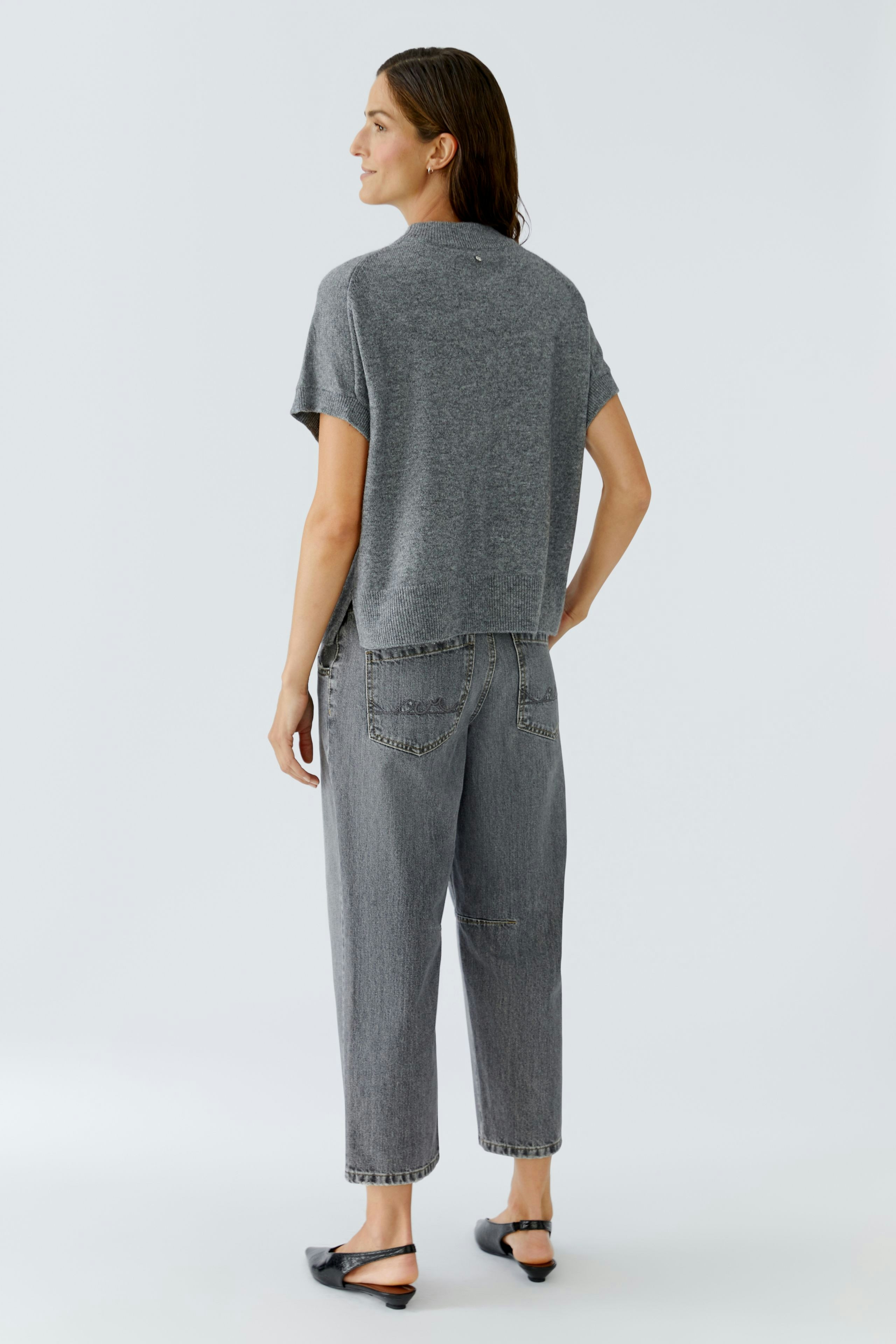 Casual women's pullover: A woman in a gray short-sleeve pullover, paired with relaxed-fit jeans.