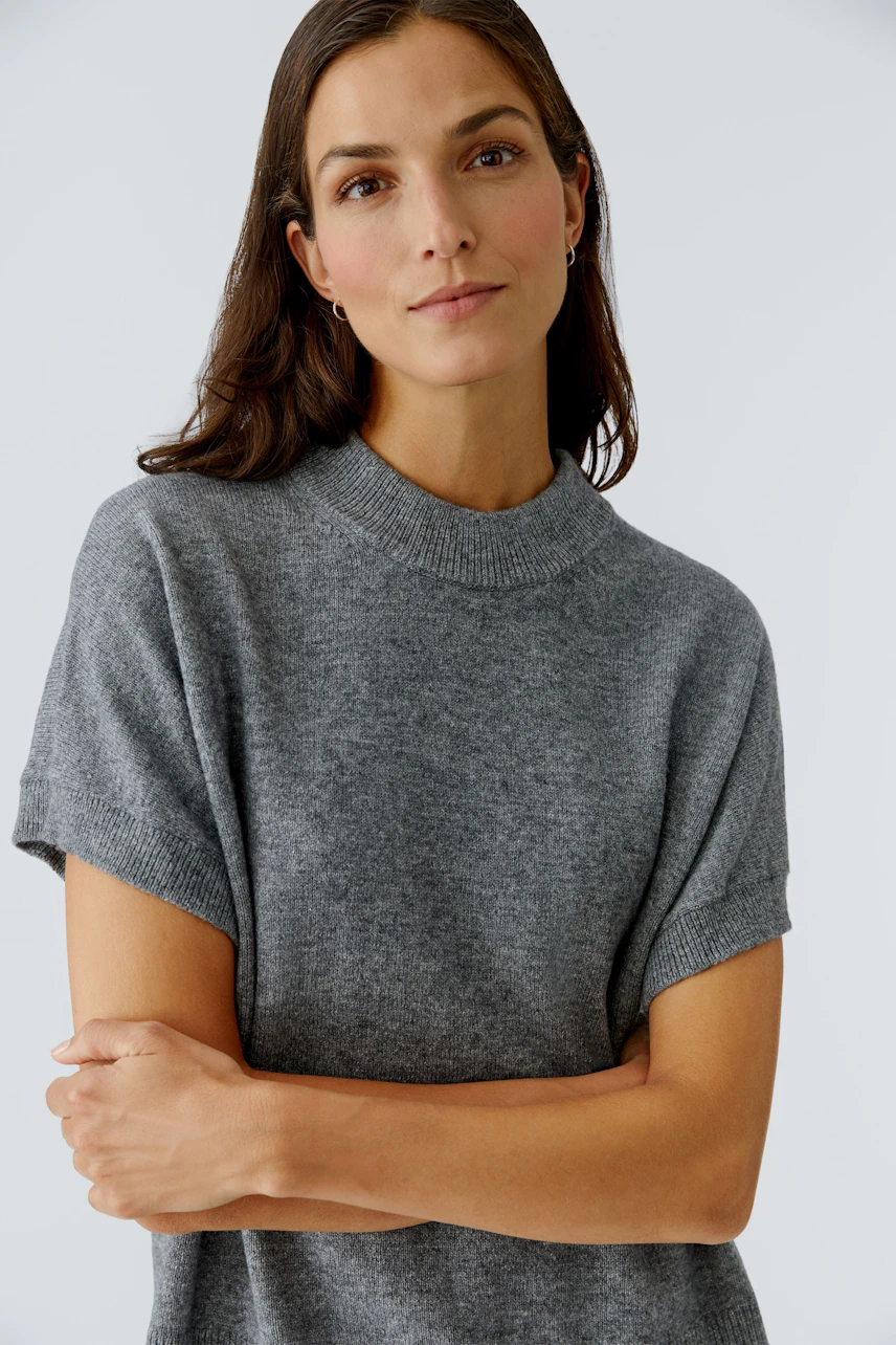 Damen-Pullover: Frau in grauem, lässigem Pullover mit kurzen Ärmeln und Rundhalsausschnitt.