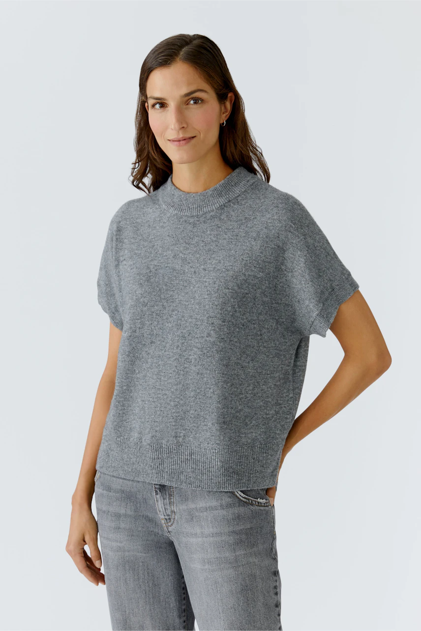 Damen-Pullover: Frau in grauem, lässigem Strickpullover mit kurzen Ärmeln und lockerer Passform.