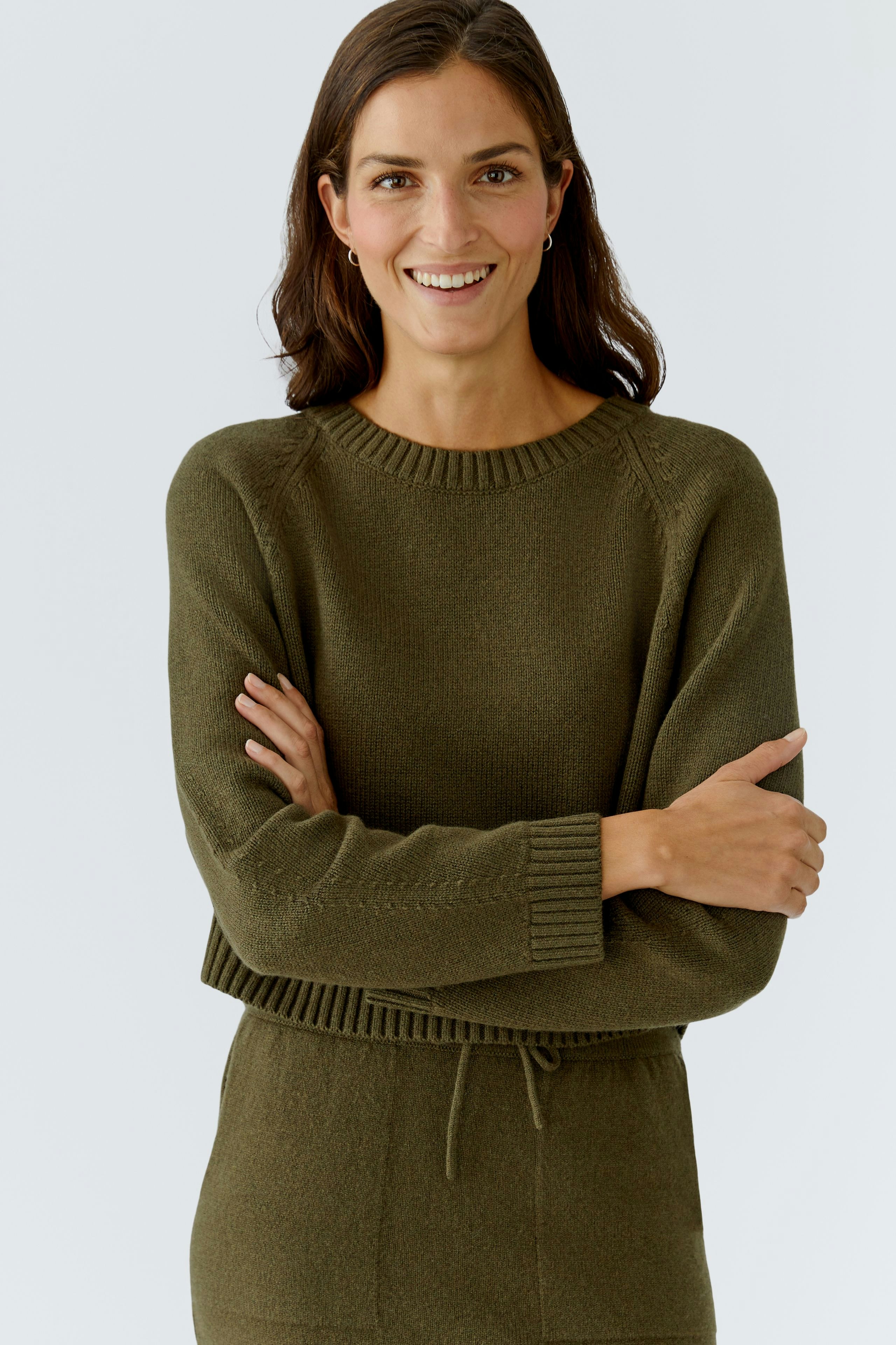 Casual women's pullover: Smiling woman in a green knitted pullover with a relaxed fit.