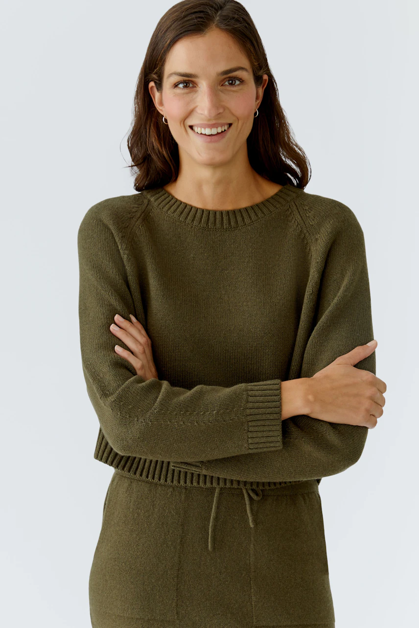 Casual women's pullover: Smiling woman in a green knitted pullover with a relaxed fit.