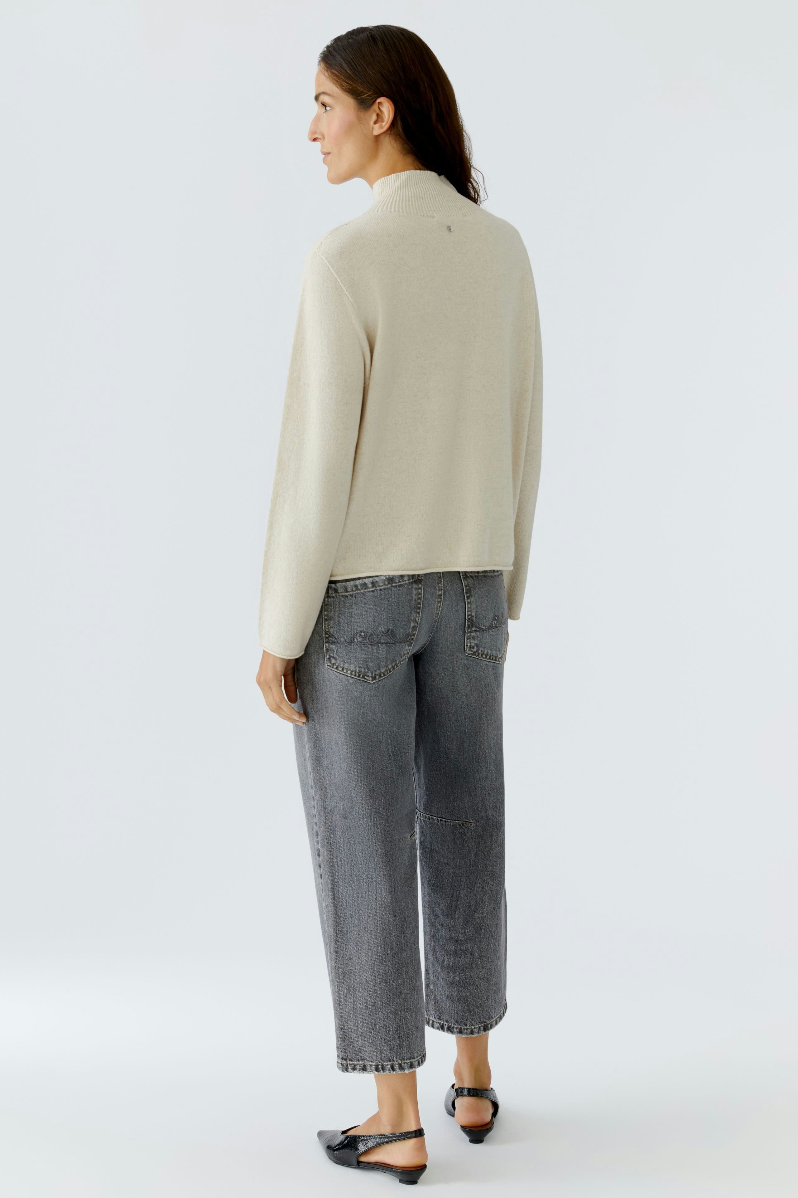 Casual women's pullover: A woman in a light beige pullover paired with relaxed-fit gray jeans.
