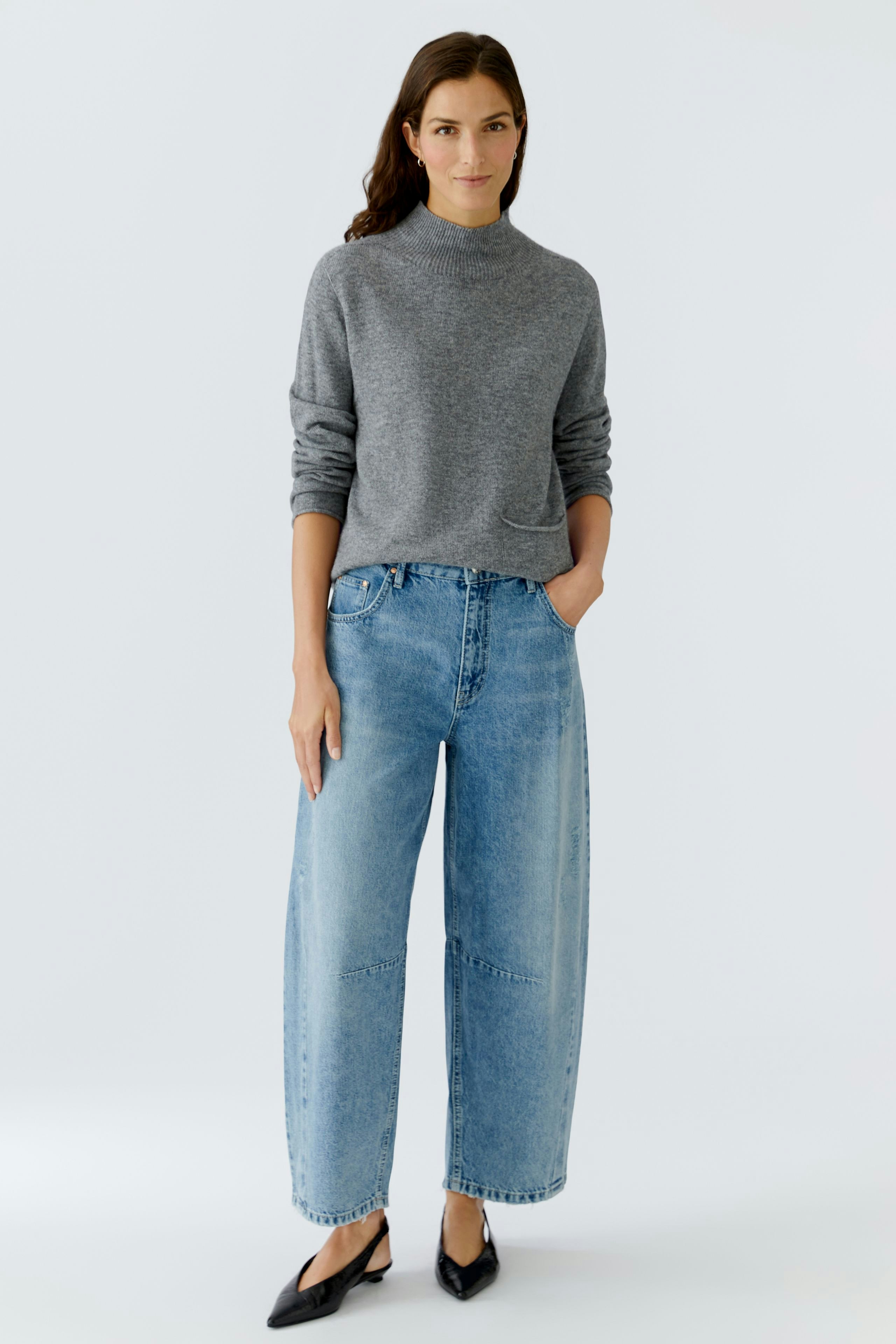 Casual women's pullover: Woman in a gray pullover with relaxed fit, paired with wide jeans.
