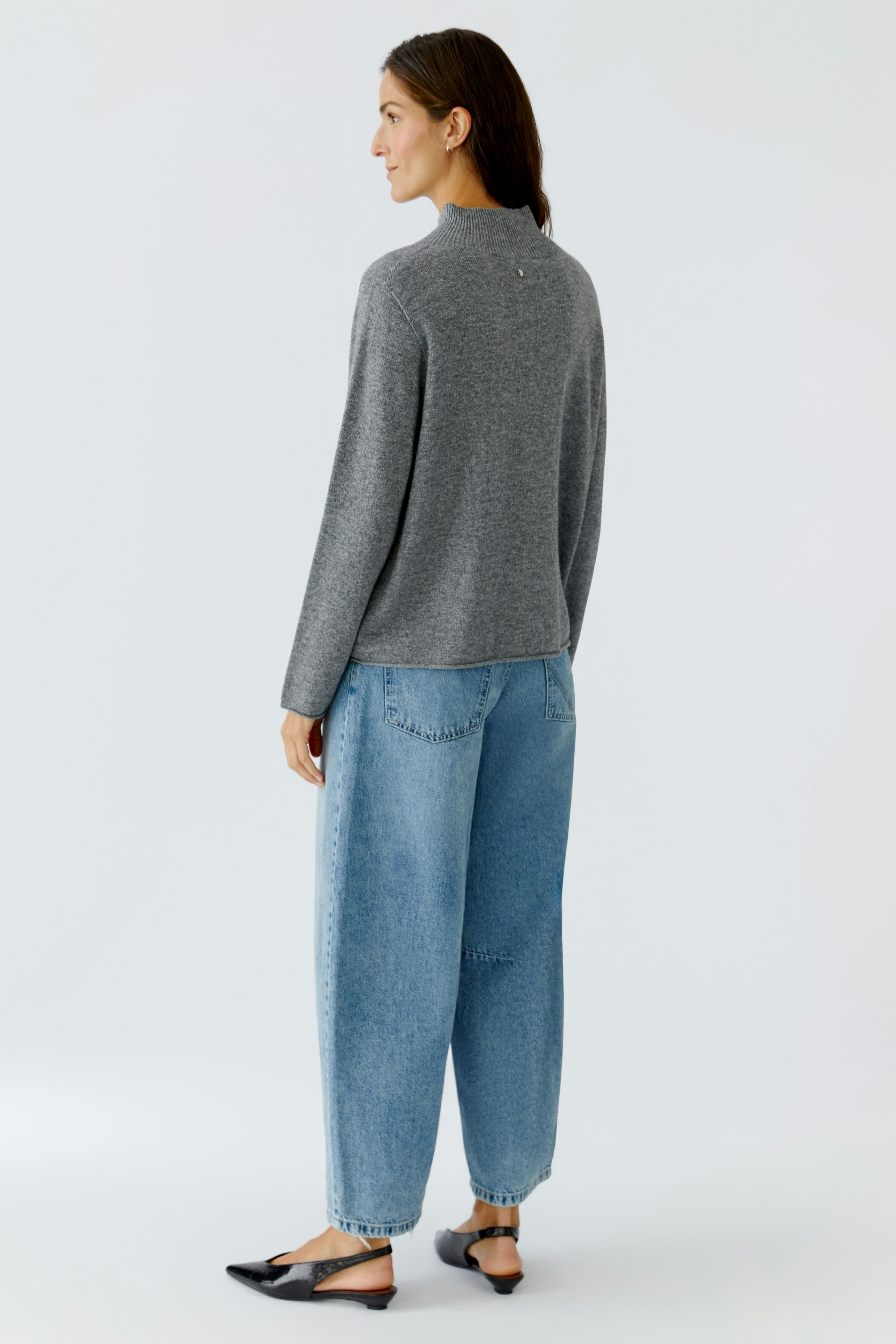 Casual women's pullover: A woman in a gray pullover paired with relaxed-fit jeans, showcasing a comfortable style.