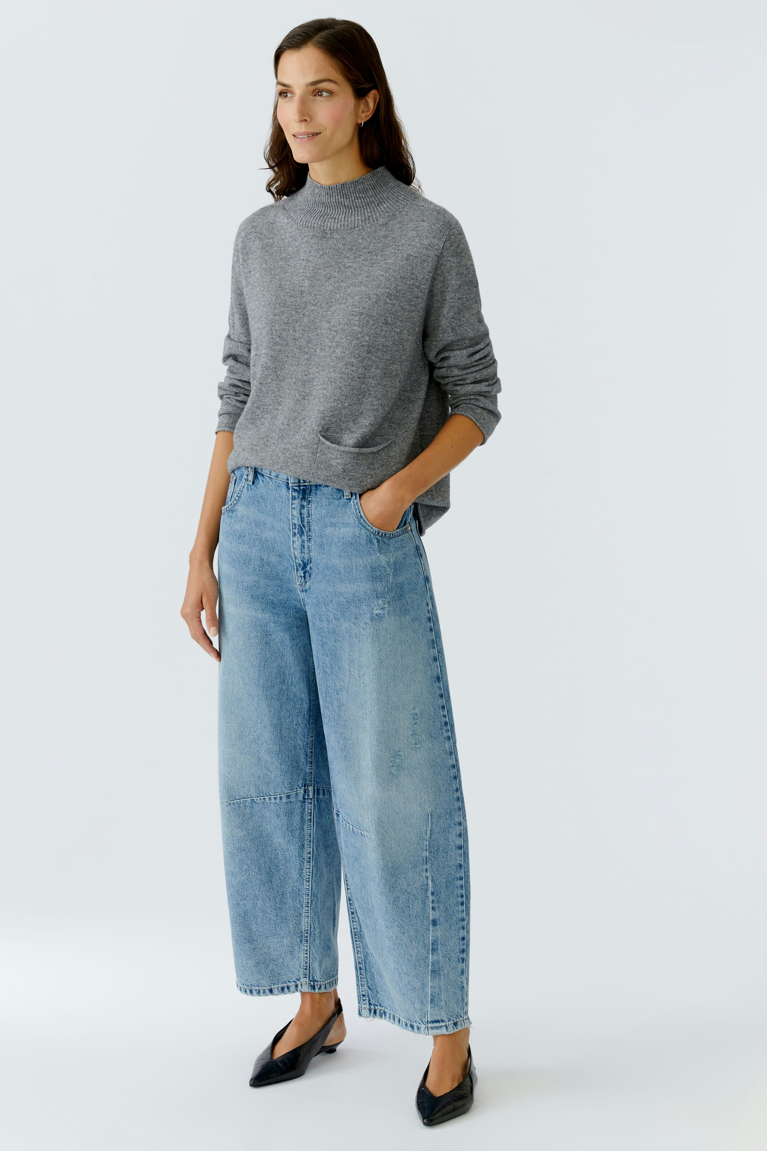 Casual women's pullover: A woman in a gray pullover paired with wide-leg jeans stands confidently.