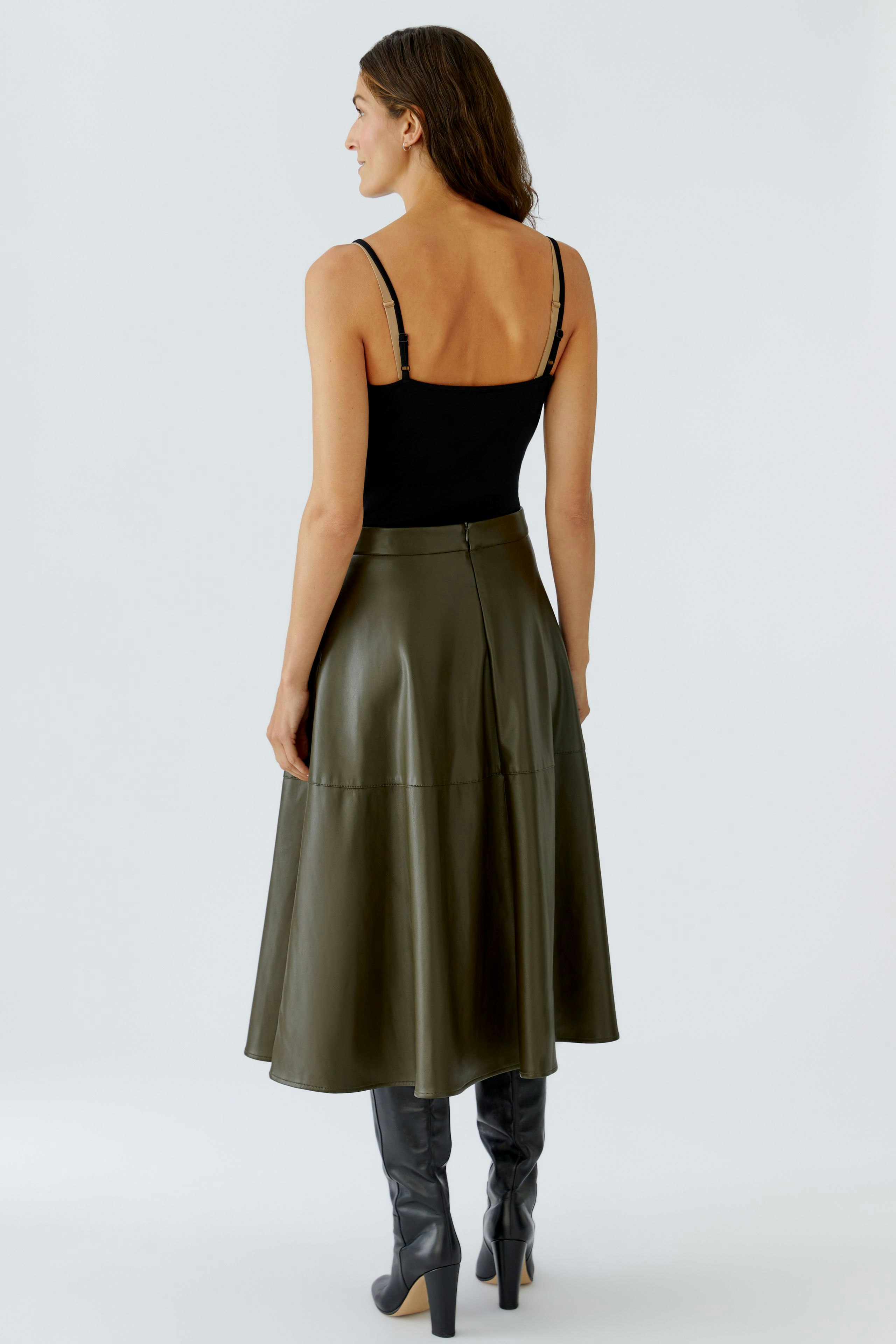 A-line skirt: Woman in a black top and olive green skirt, showcasing a relaxed style.