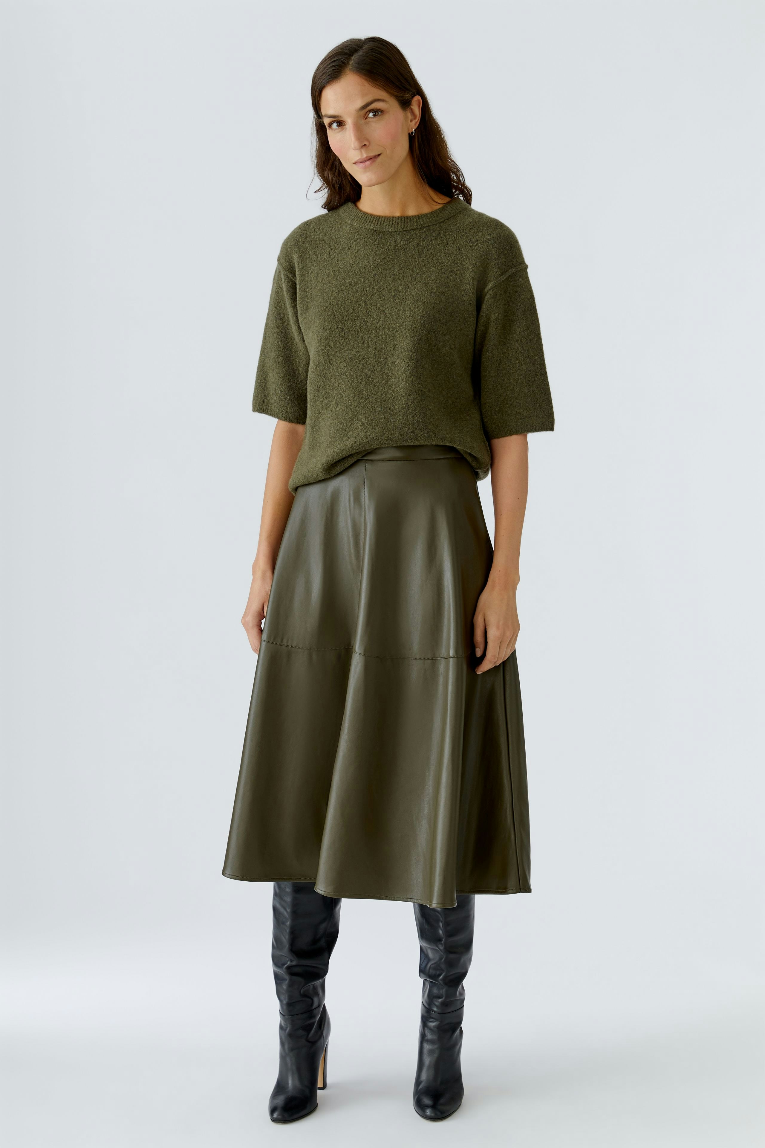 A-line skirt: Woman in a green top and a long, dark skirt, showcasing a casual style.