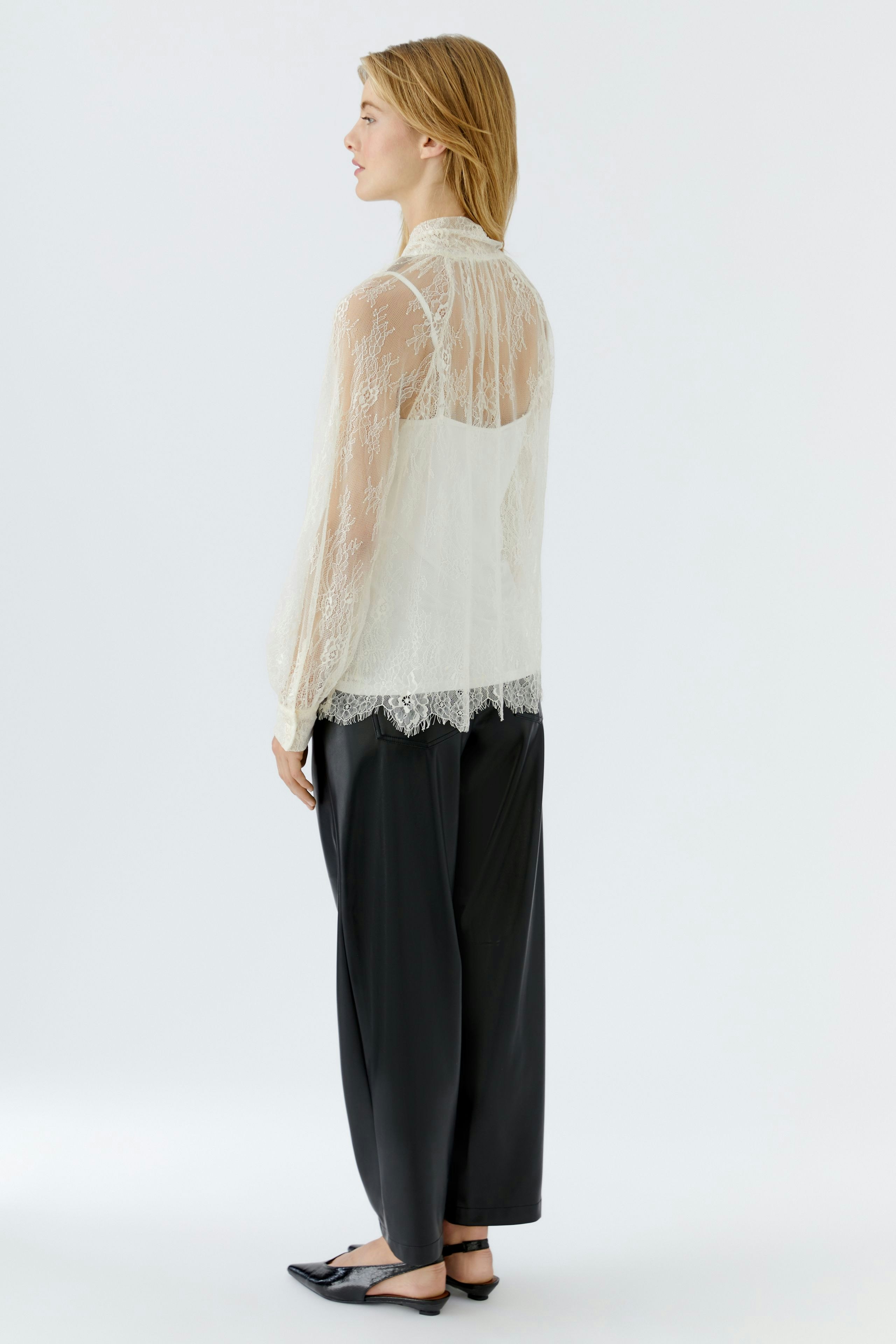 Lightweight blouse: Woman in a sheer lace blouse paired with denim shorts and knee-high boots.