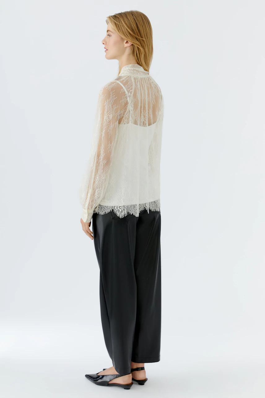 Lightweight blouse: Woman in a sheer lace blouse paired with denim shorts and knee-high boots.