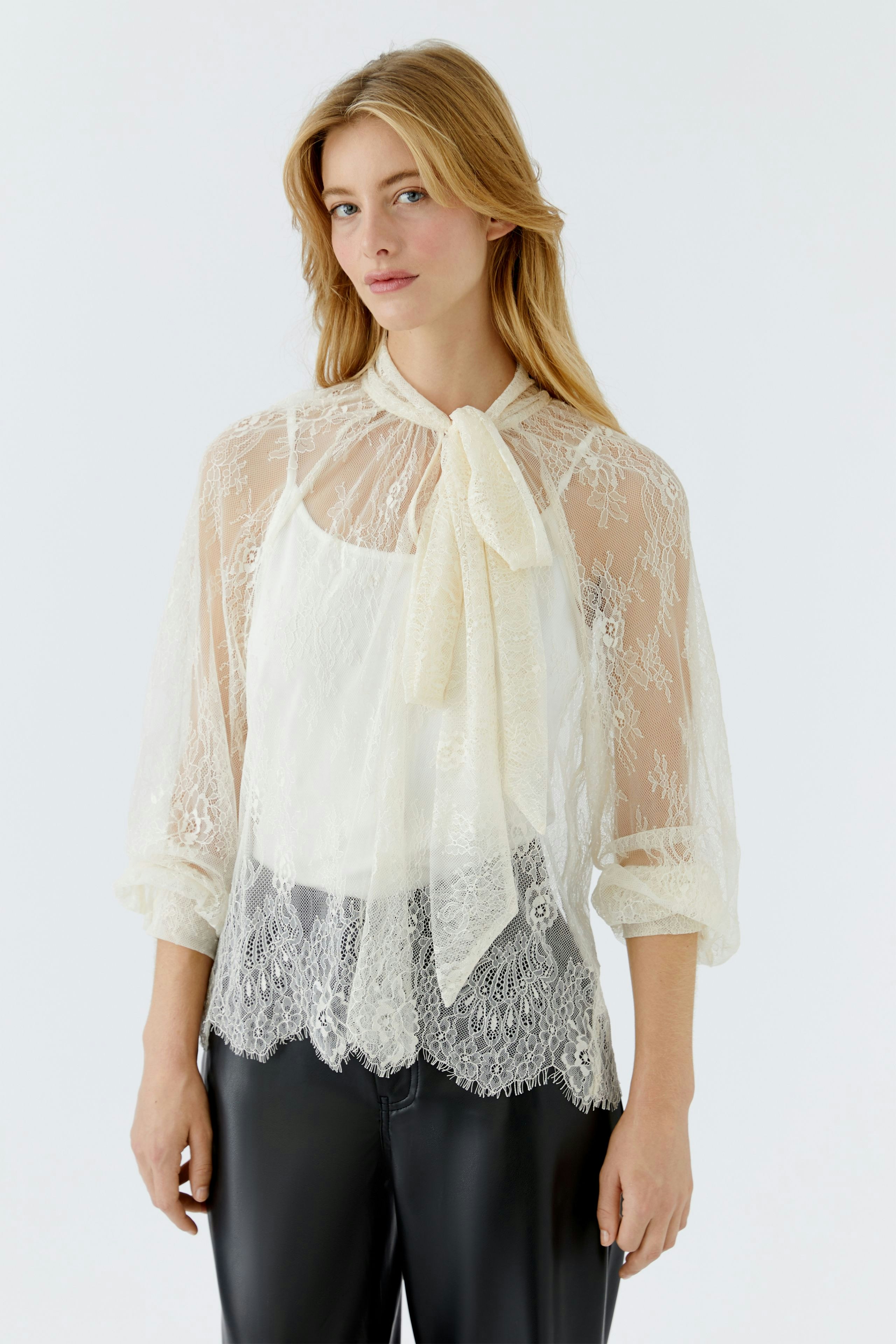 Lace blouse: Woman wearing a delicate lace blouse with intricate details, paired with denim.