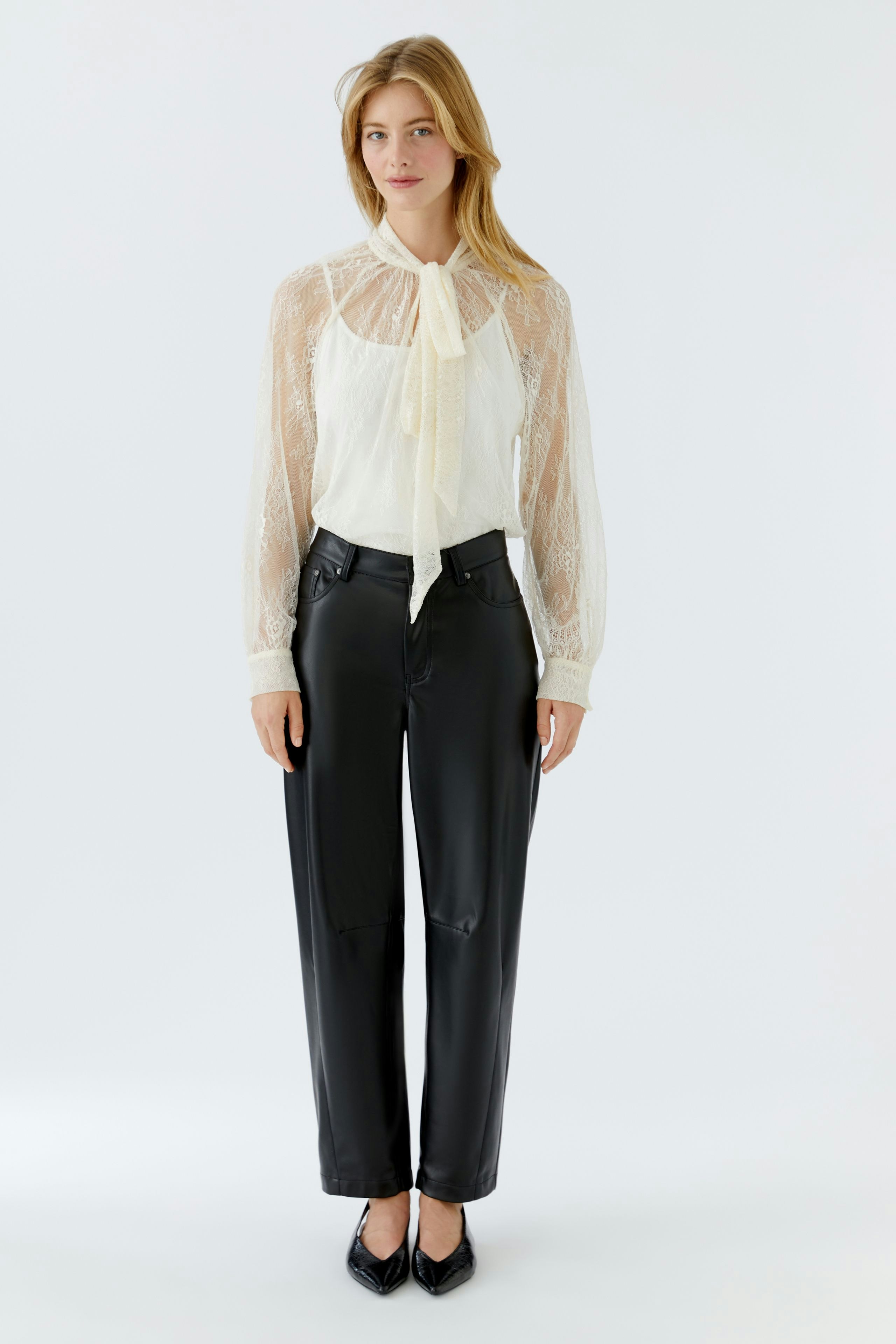 Light blouse with a tie detail, worn by a woman, paired with wide jeans and knee-high boots.