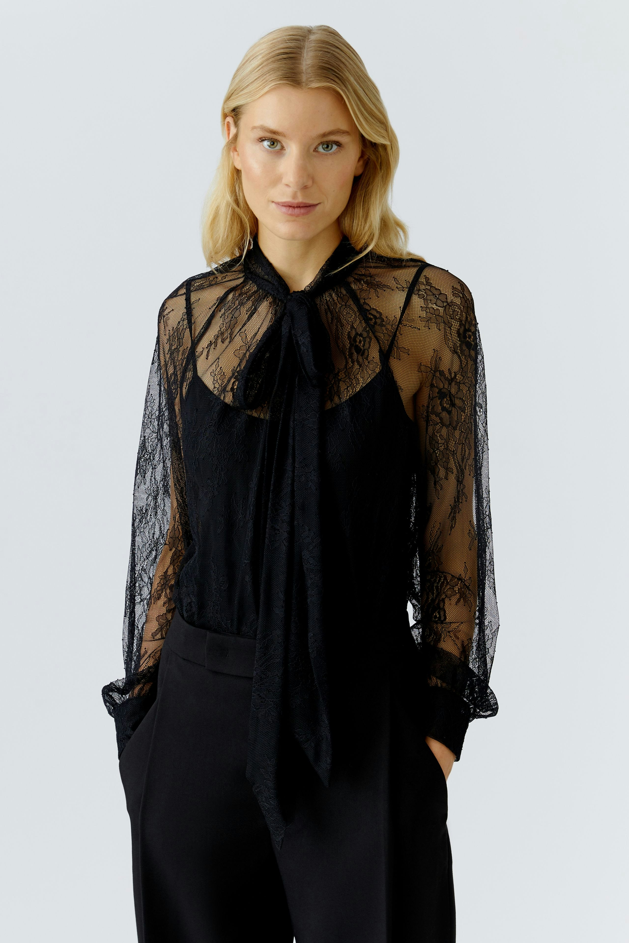 Stylish women's blouse: Woman in a black lace blouse with a tie detail and relaxed fit.