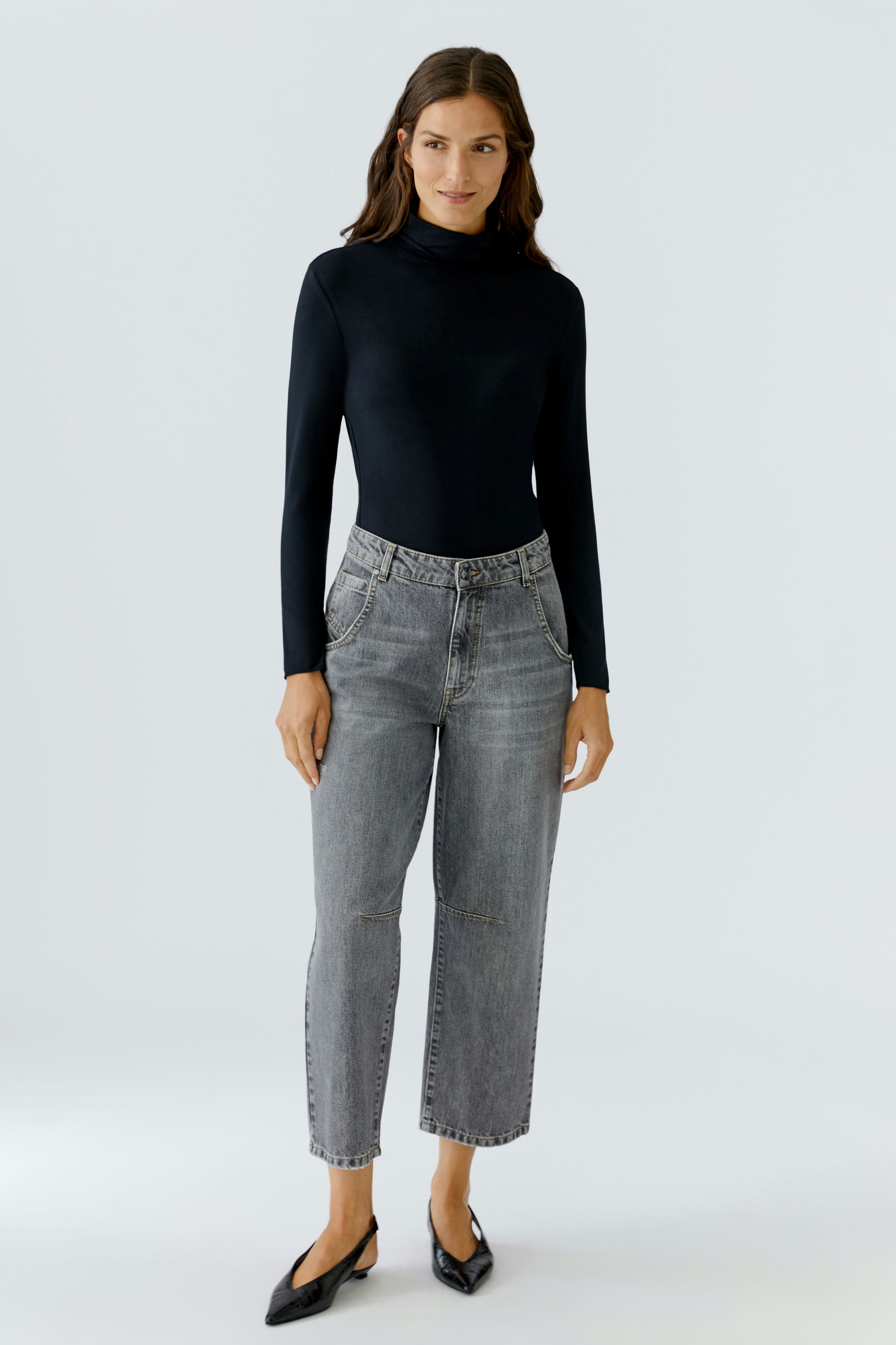 Casual women's long-sleeve shirt: A woman in a fitted black top paired with gray jeans, exuding a relaxed vibe.