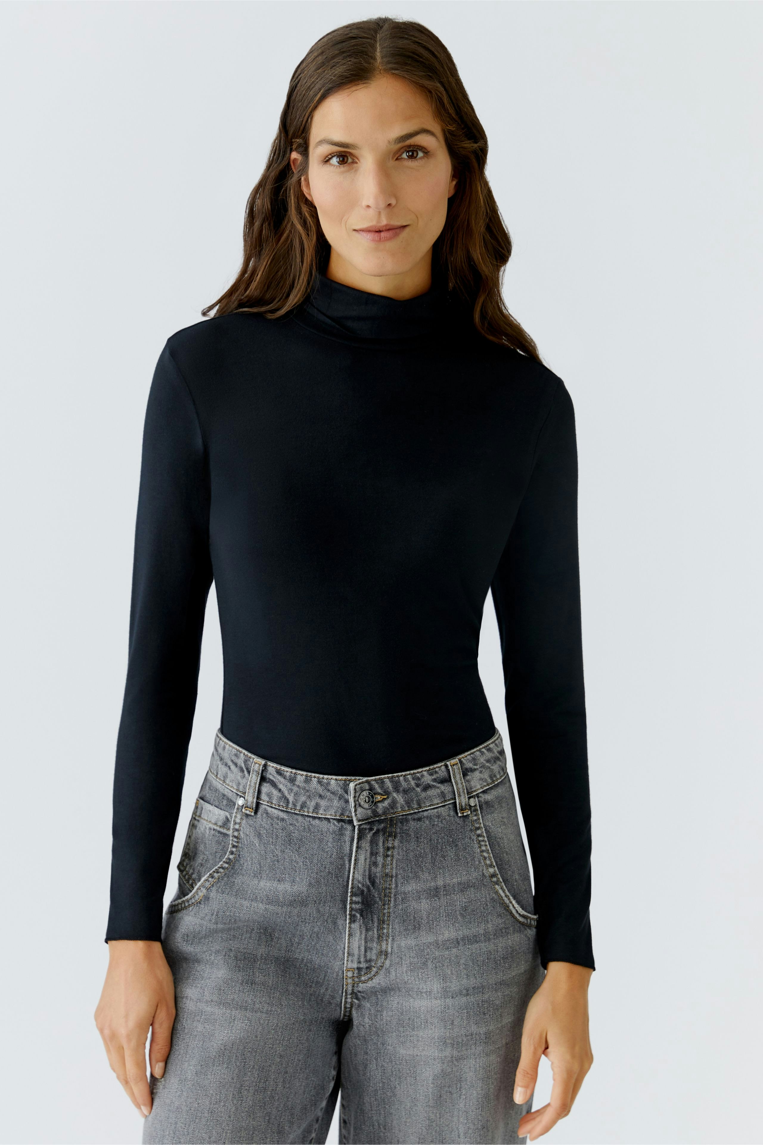 Long-sleeve shirt: Woman in a black turtleneck top paired with gray jeans, showcasing a casual style.