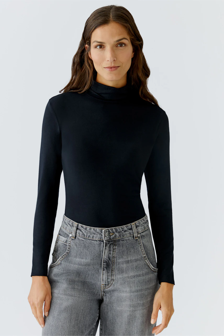 Long-sleeve shirt: Woman in a black turtleneck top paired with gray jeans, showcasing a casual style.