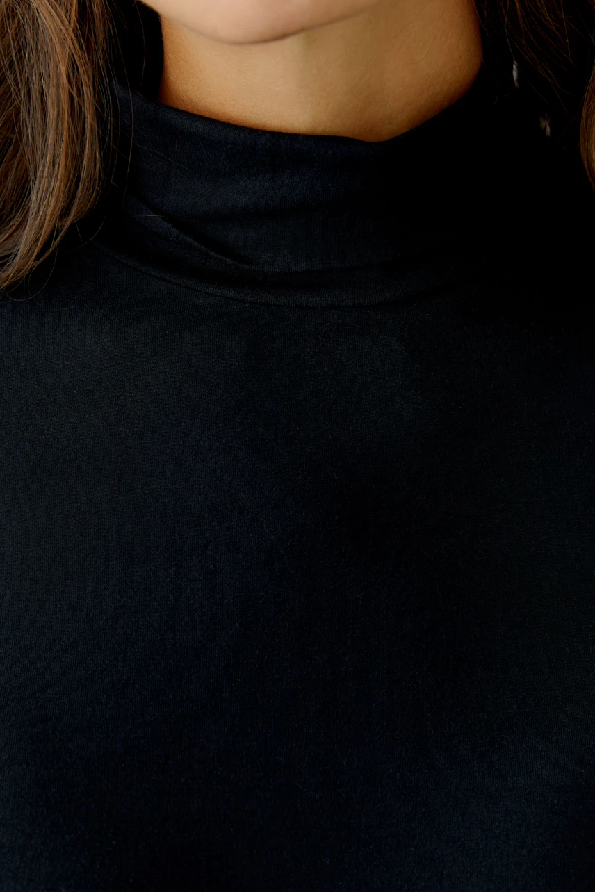 Casual women's long-sleeve shirt: Close-up of a woman in a black top with a high collar.