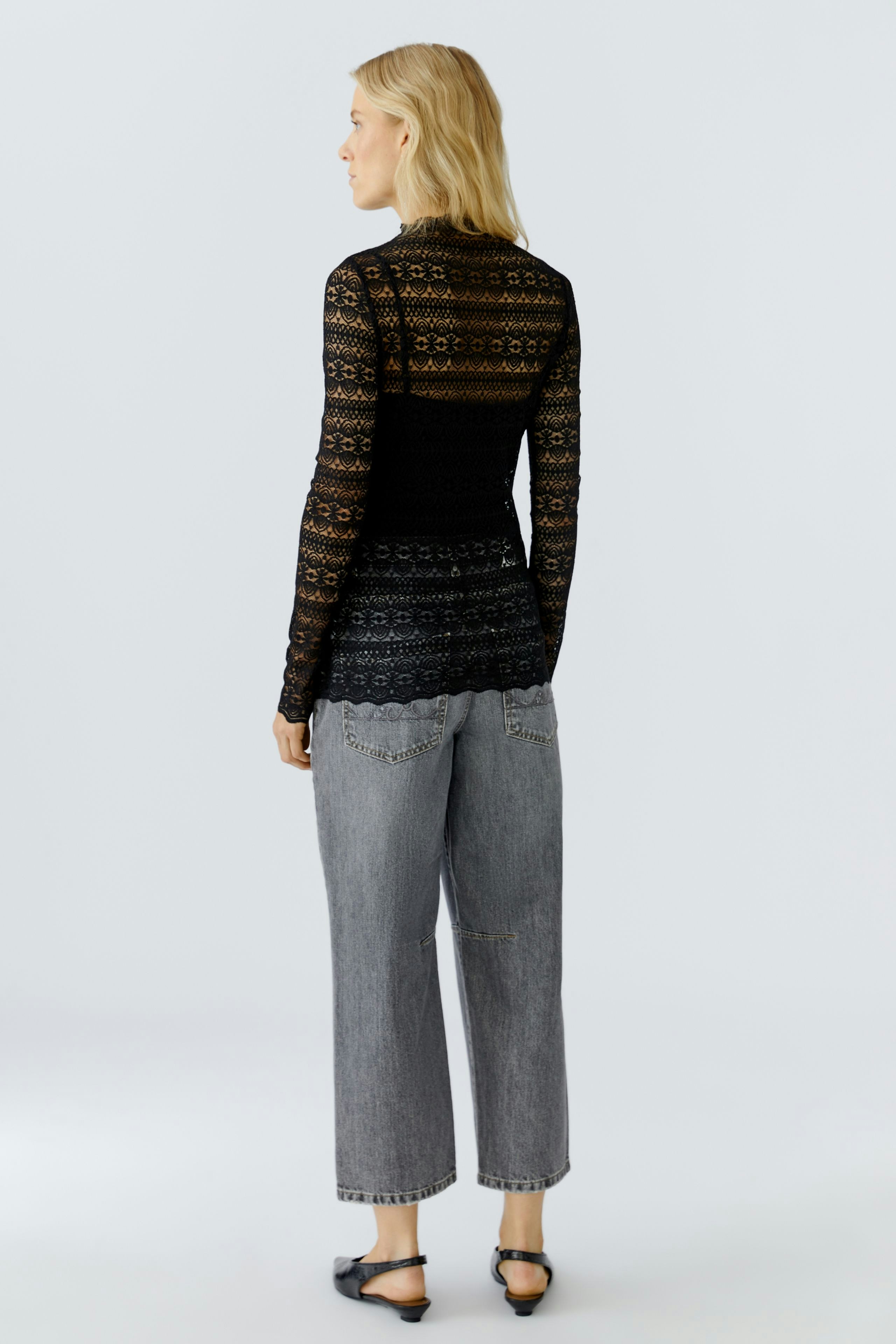 Stylish women's long-sleeve shirt: A woman in a black lace top paired with relaxed-fit jeans.