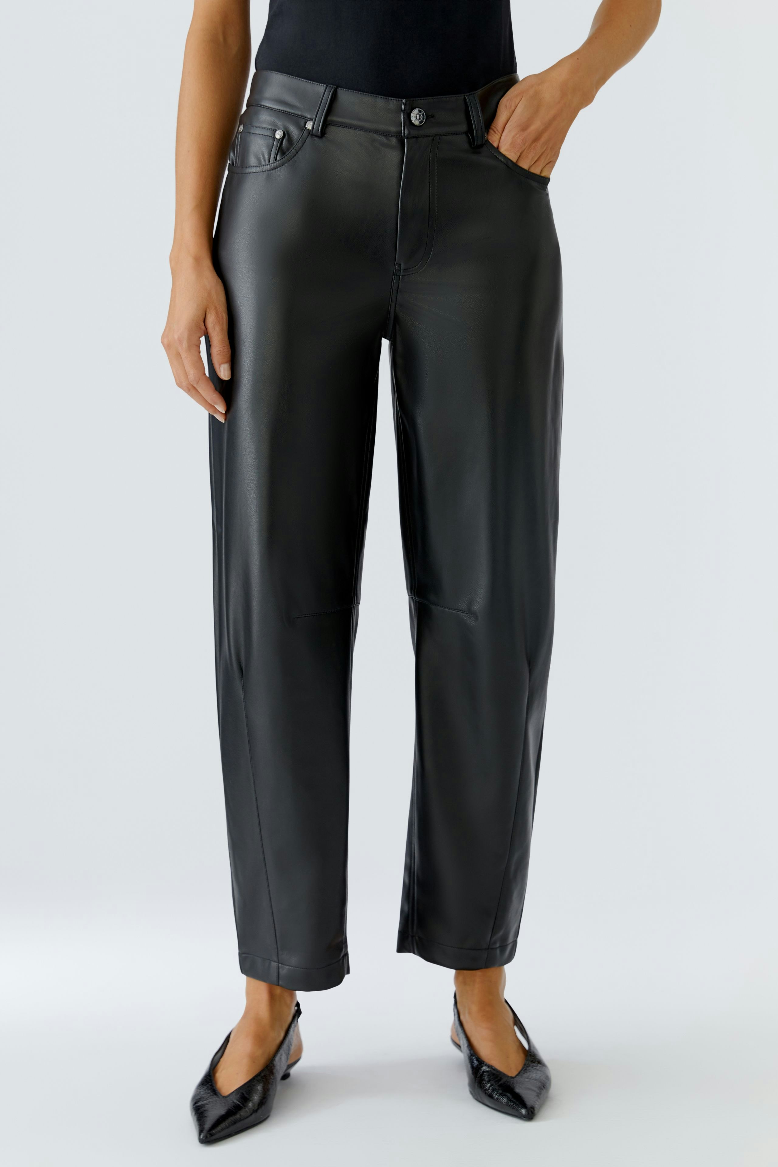 Trendy faux leather pants: Woman in black pants with a relaxed fit and classic five-pocket design.