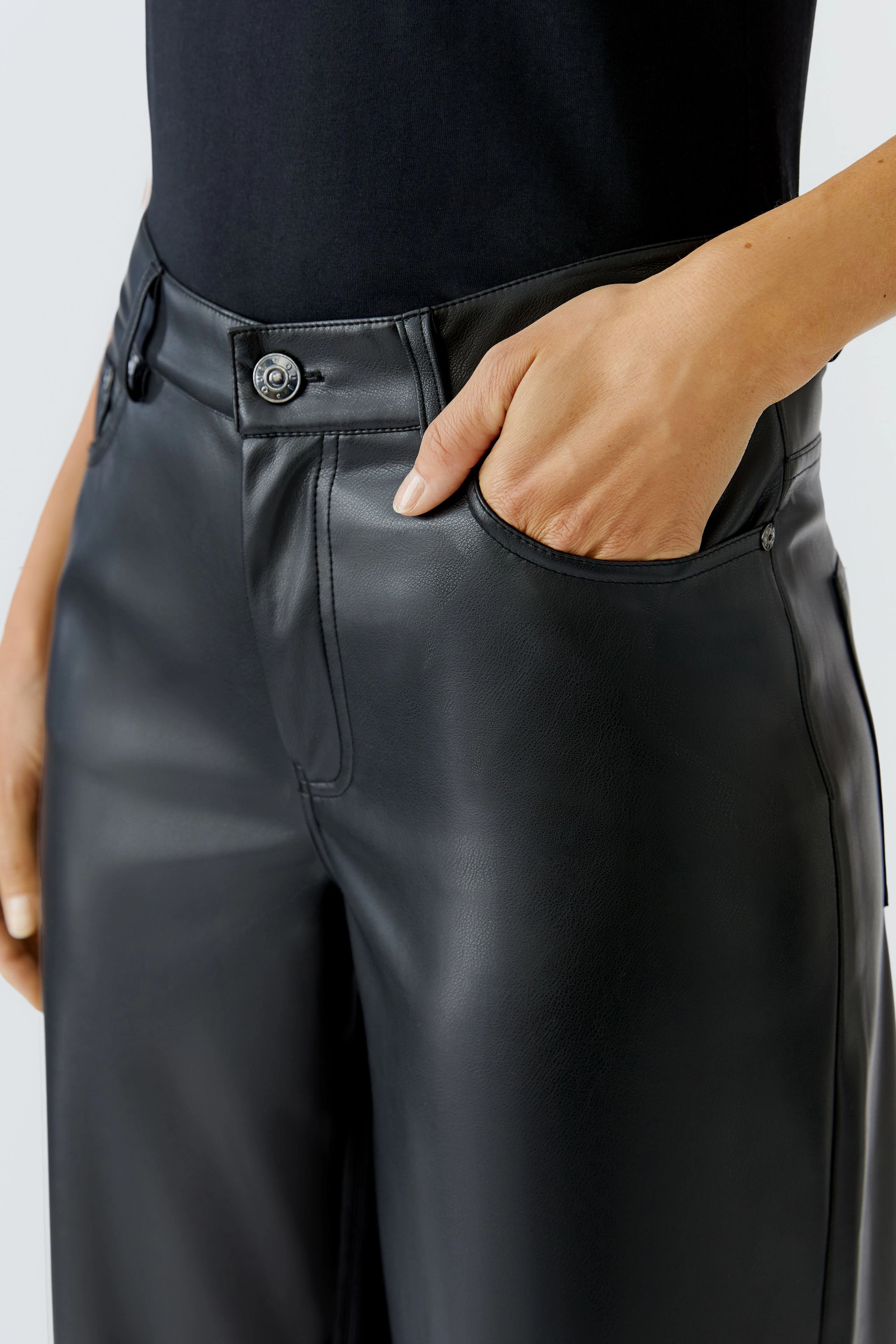 Schwarze Lederimitathose: Frau mit Hand in der Tasche, lässiger Look, ideal für den Alltag.