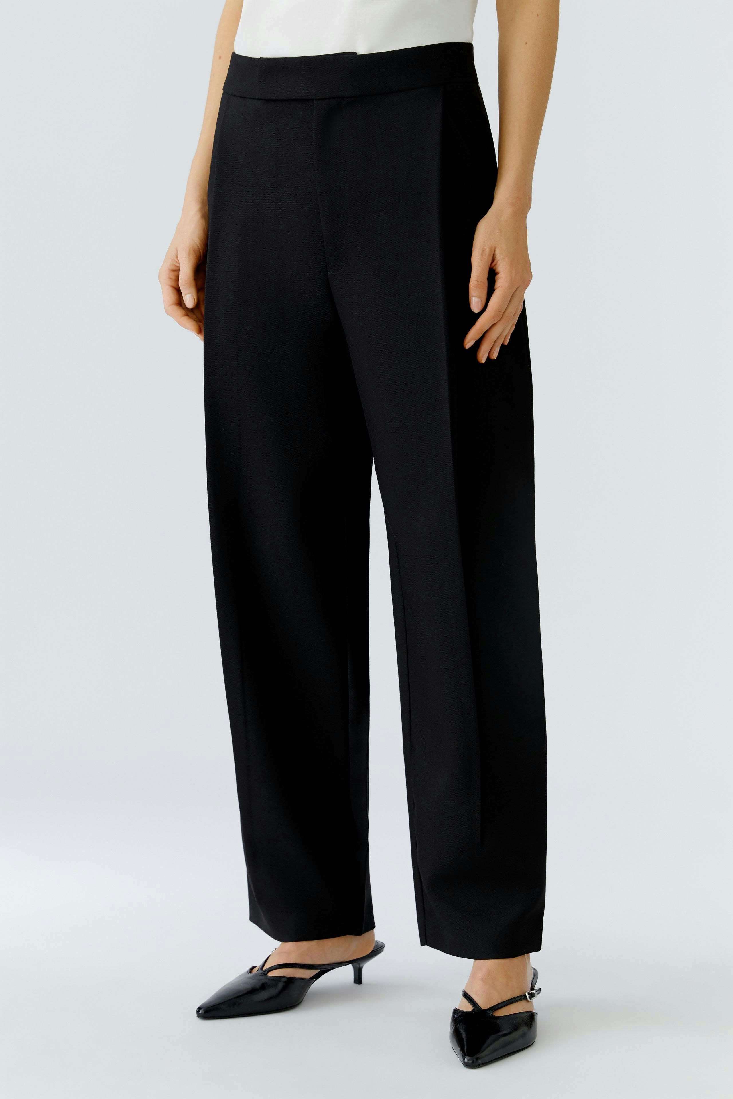 Tailored women's pleated trousers in black, featuring a high waist and a relaxed fit.