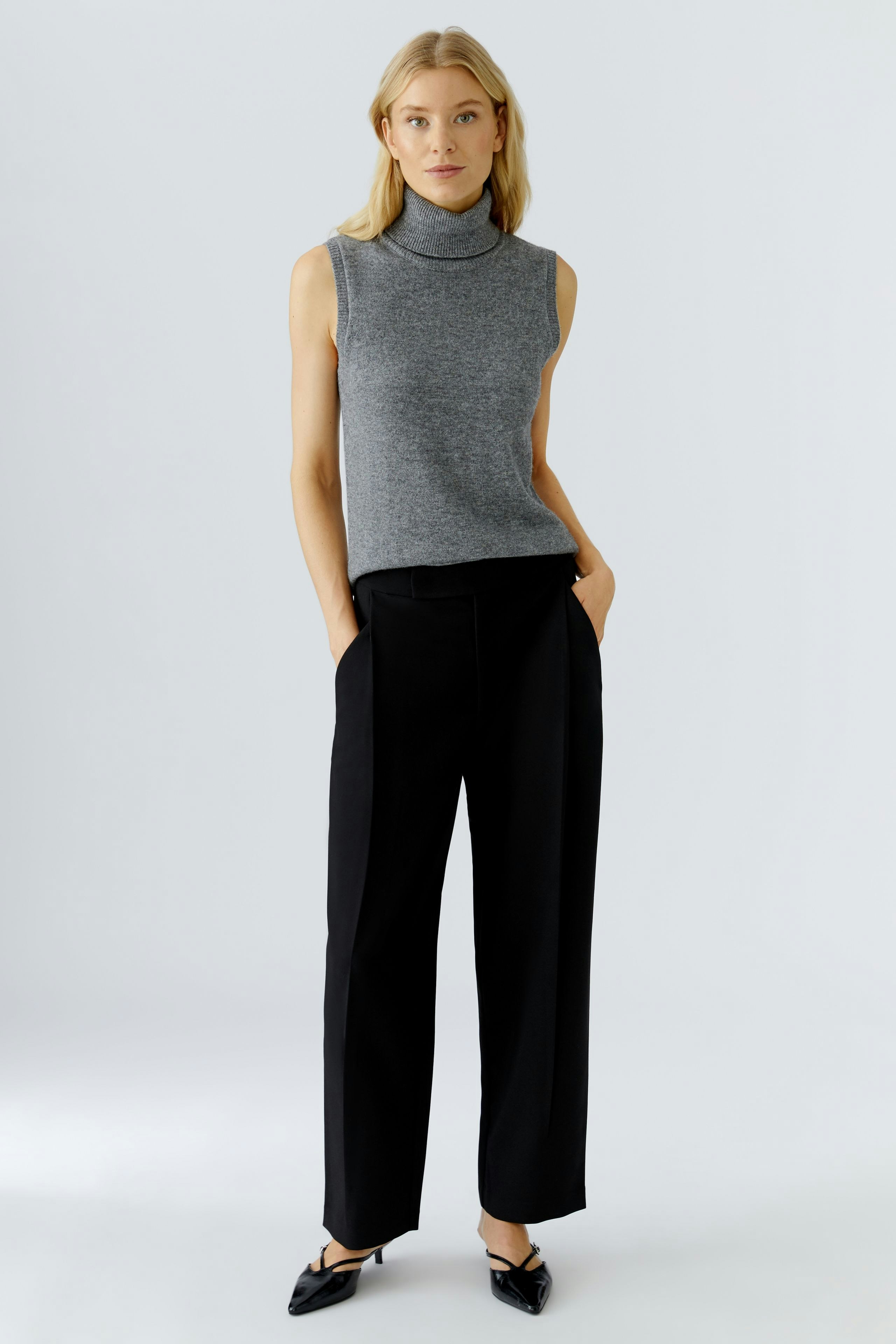 Stylish women's pleated trousers: A woman in black trousers with a relaxed fit and pockets.