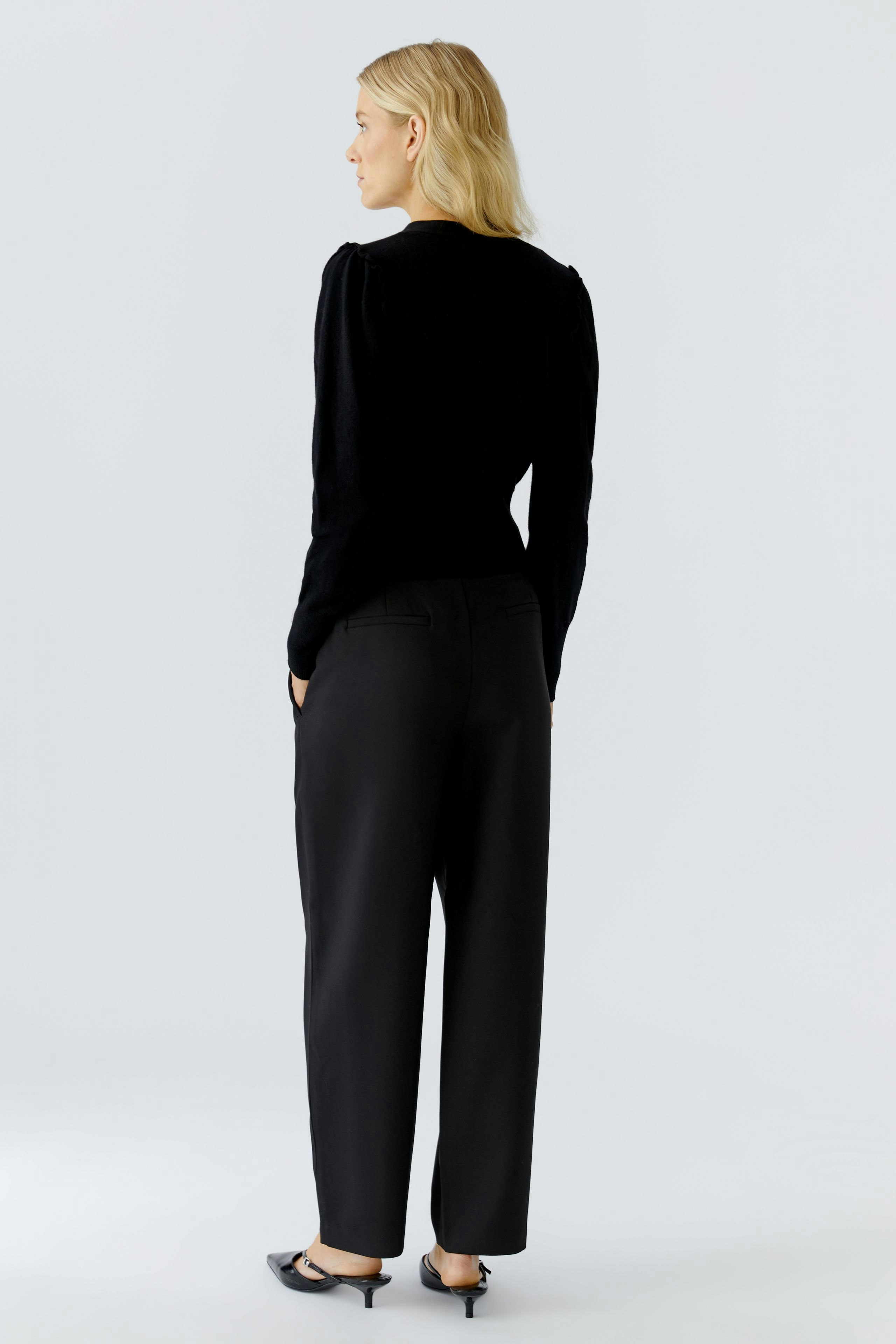 Casual women's cardigan: A woman in a black cardigan with a relaxed fit, paired with loose trousers.