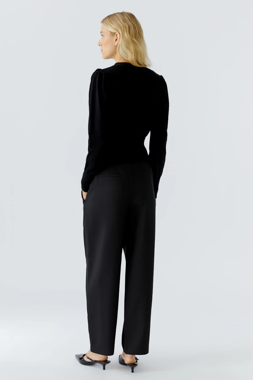 Casual women's cardigan: A woman in a black cardigan with a relaxed fit, paired with loose trousers.