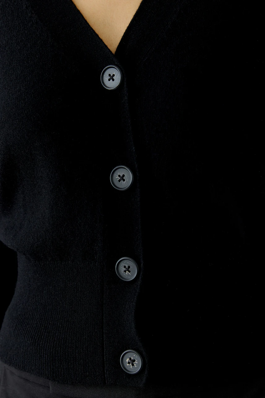 Casual women's cardigan: A woman in a black cardigan with buttons, perfect for layering.