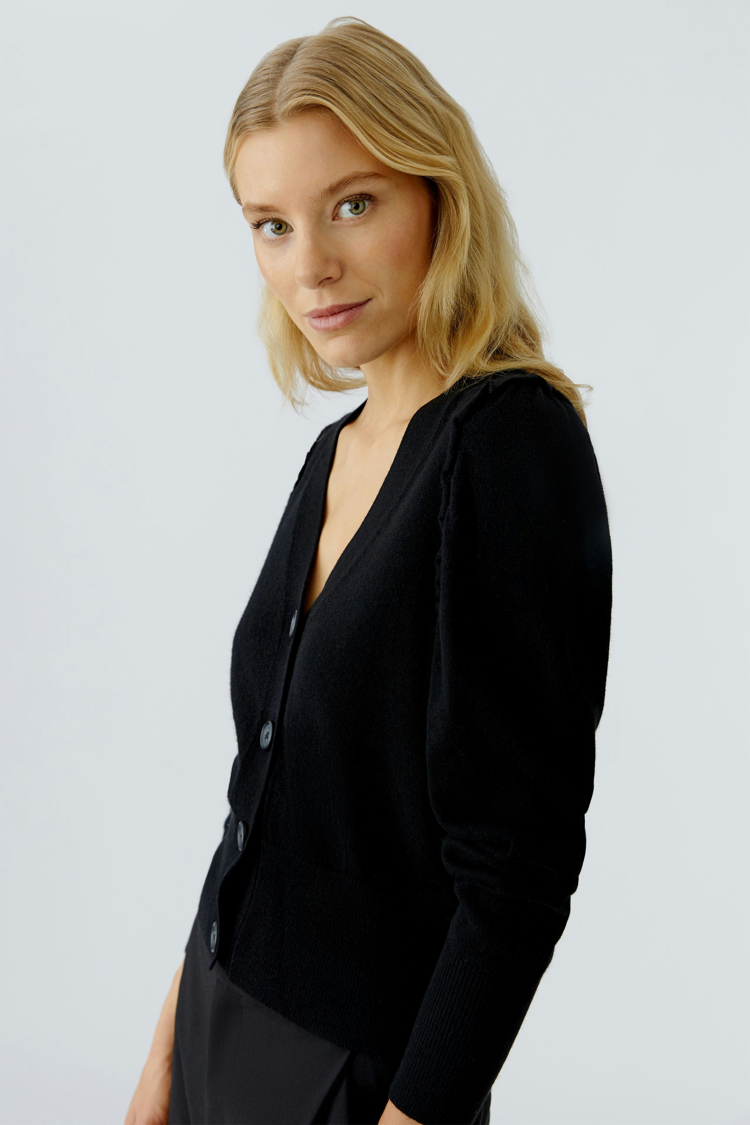 Casual women's cardigan: A woman in a black cardigan with buttons, looking confidently at the camera.
